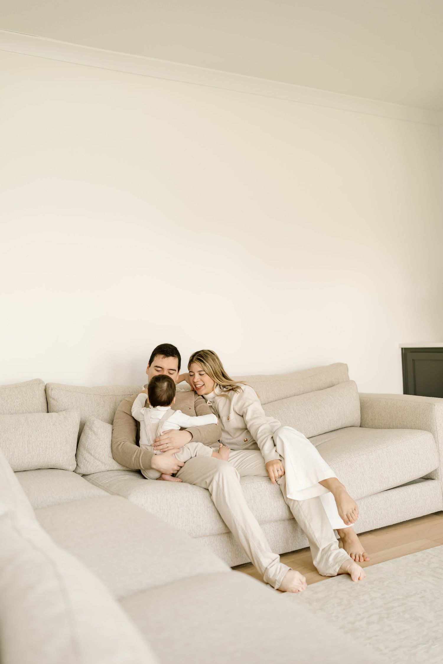Two people in white clothing lounging together on a modern white sofa in a minimalist setting.