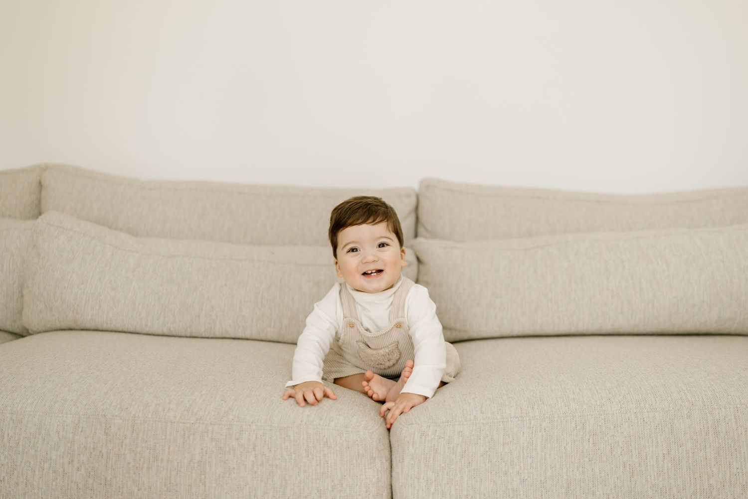A series of photos showing a small child crawling and playing on a beige couch.