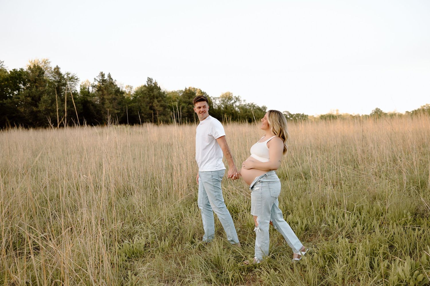 People walk together through a golden field at sunset, creating a dreamy romantic atmosphere.