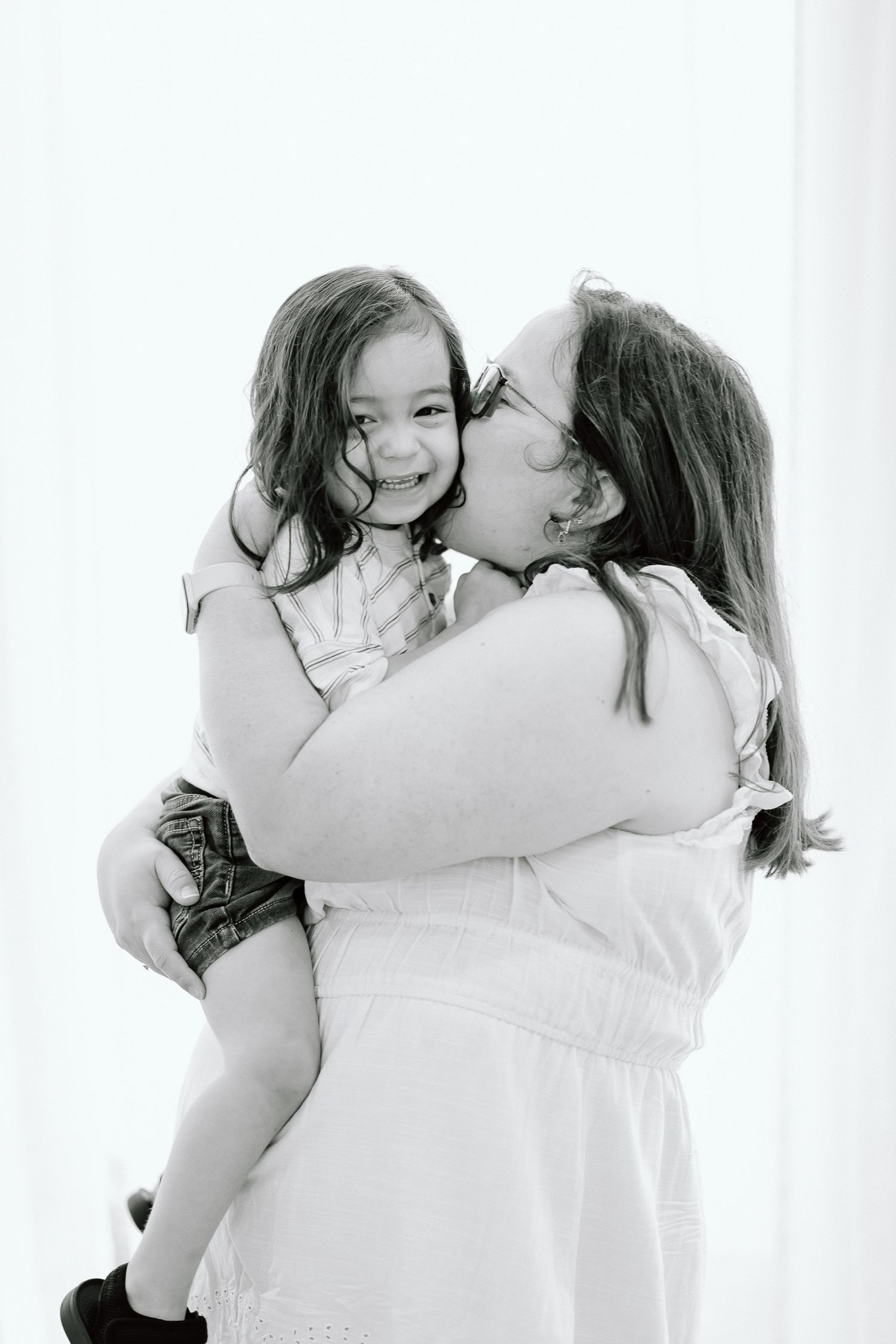 A black and white portrait capturing an intimate embrace between parent and child.