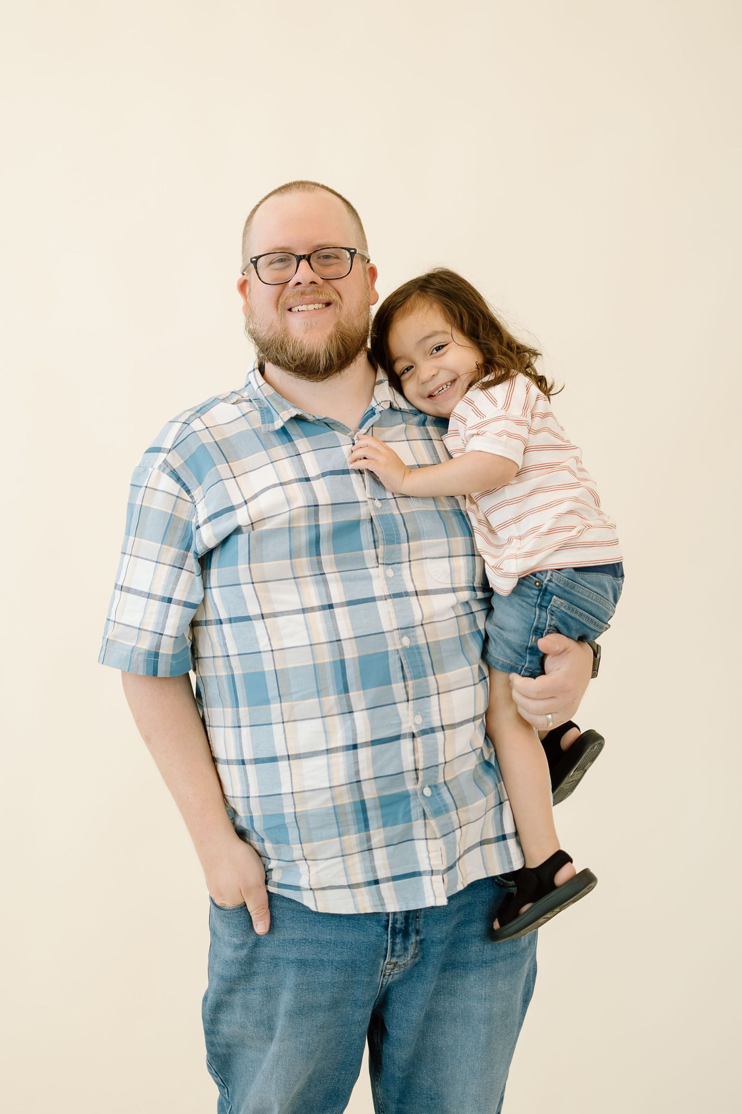 A parent and child in matching outfits pose together for a series of playful studio portraits against a light background.