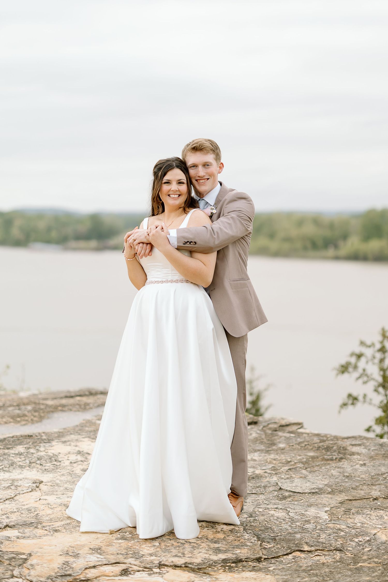 A couple shares a romantic moment on a sandy beach shore during their wedding photoshoot.