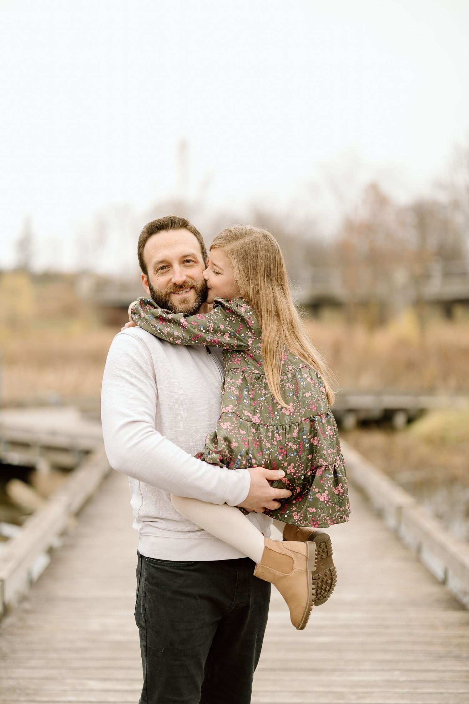 A sweet embrace between parent and child on a wooden walkway during an autumn photoshoot.