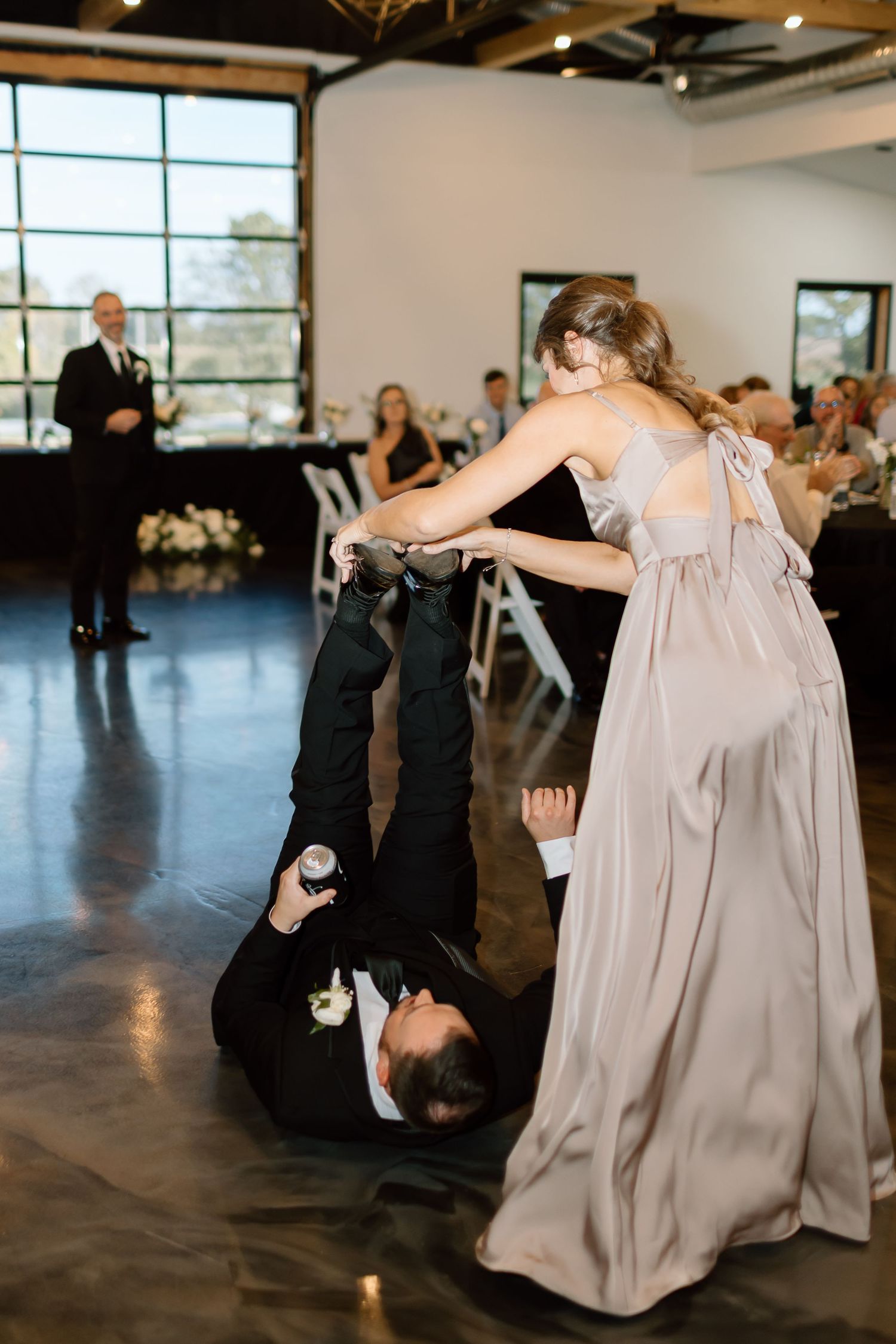 Dancers perform playful moves on a polished concrete floor during a wedding reception in a modern venue.