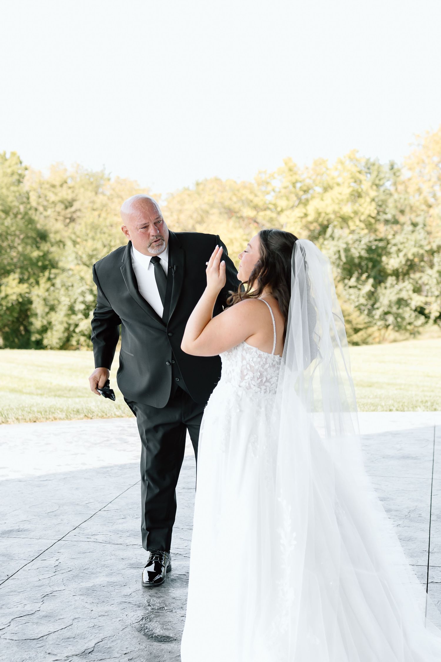 Bride and groom share a tender moment during first look photos at an outdoor wedding venue.