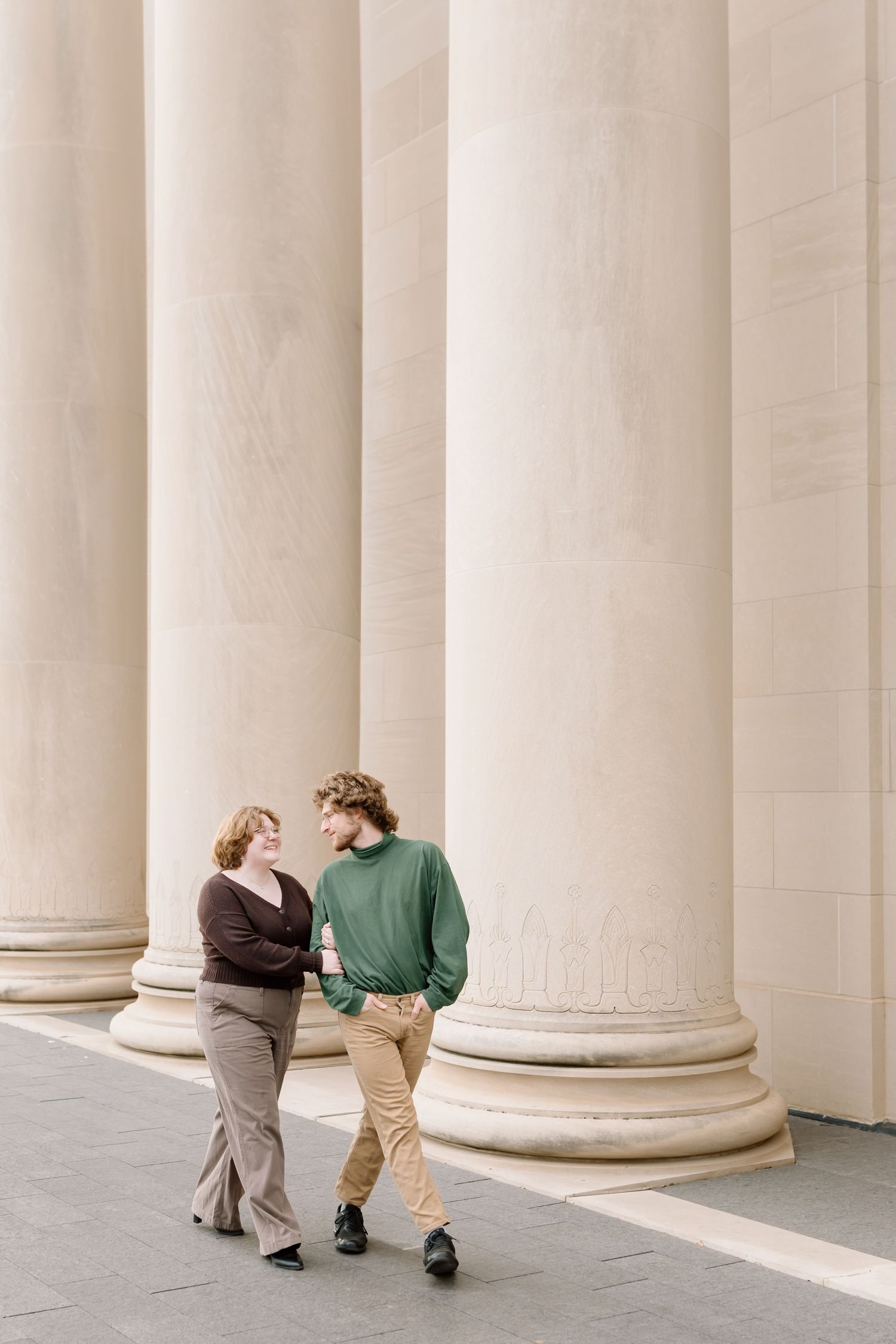 A sequence of images showing two people walking among tall white columns in an elegant colonnade.