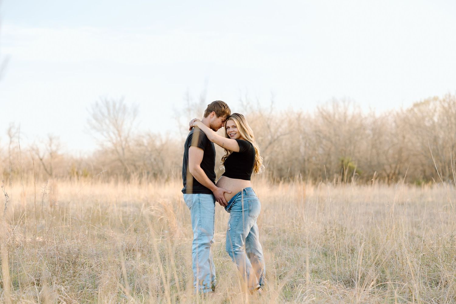 A couple embraces in a golden field during sunset creating a romantic silhouette against the warm sky.