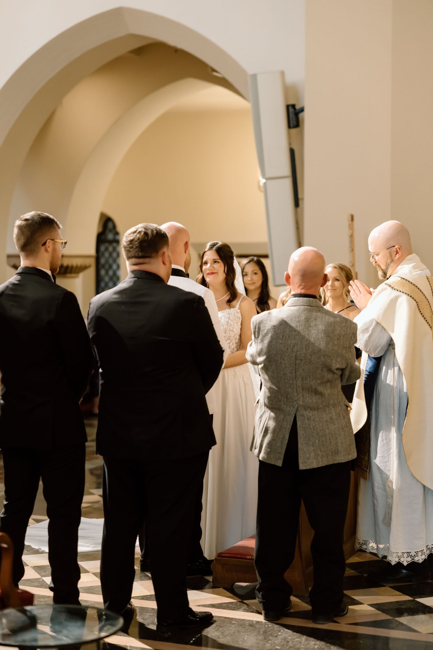 Religious ceremony participants line up against a wall under arched doorways during a solemn service.