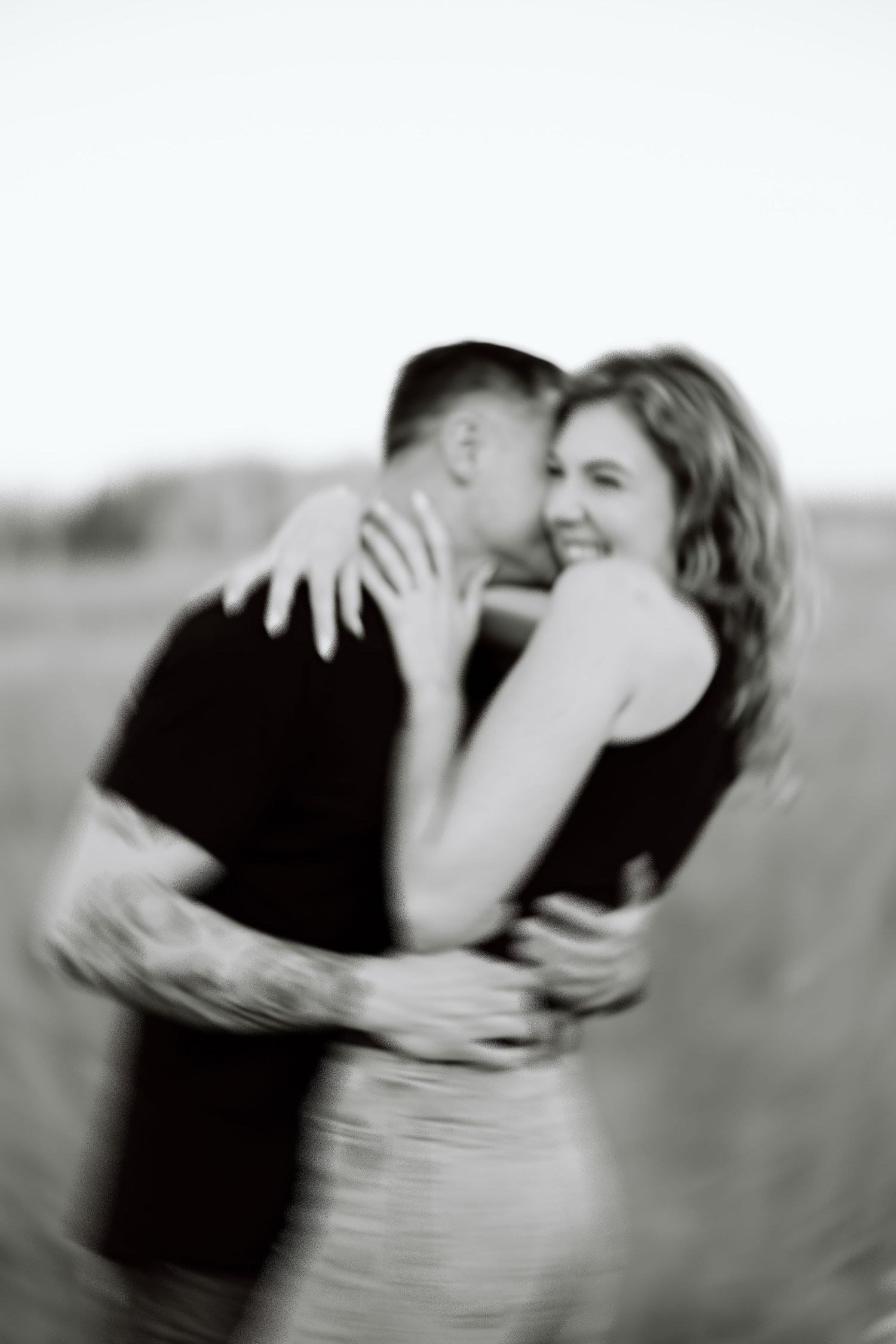 Black and white artistic series of a couple sharing intimate moments in a dreamy outdoor setting.