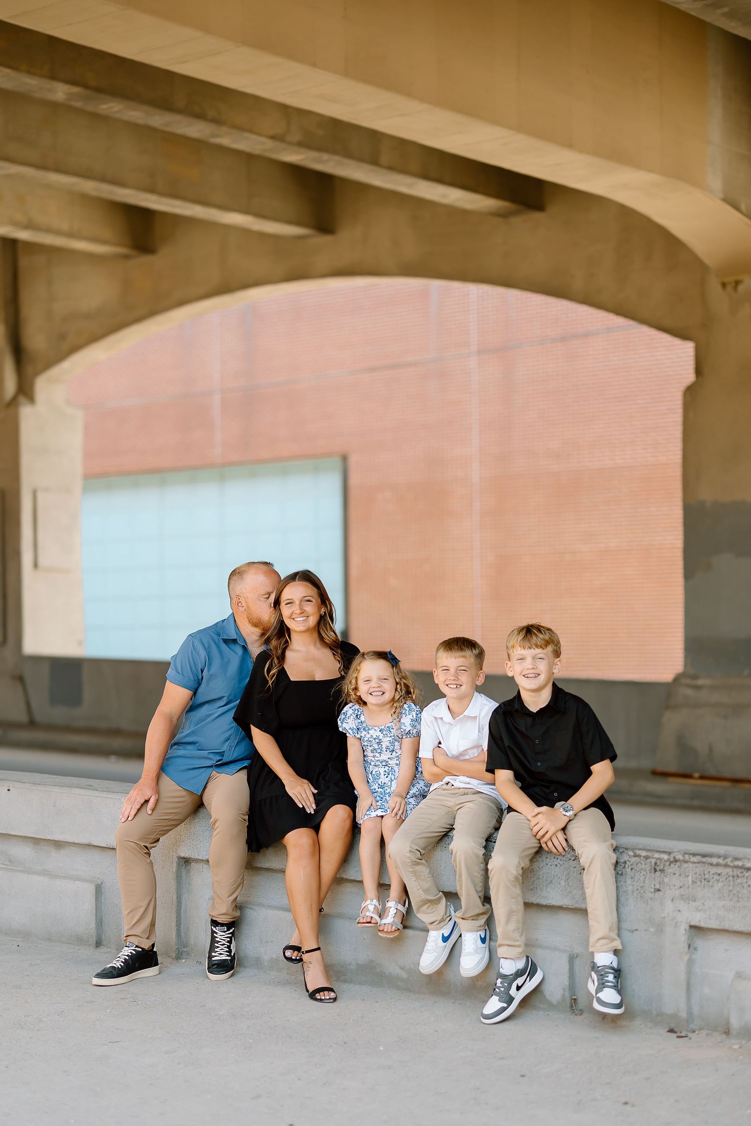 Family sitting together on concrete ledge in progressive sequence showing movement and playful interaction.