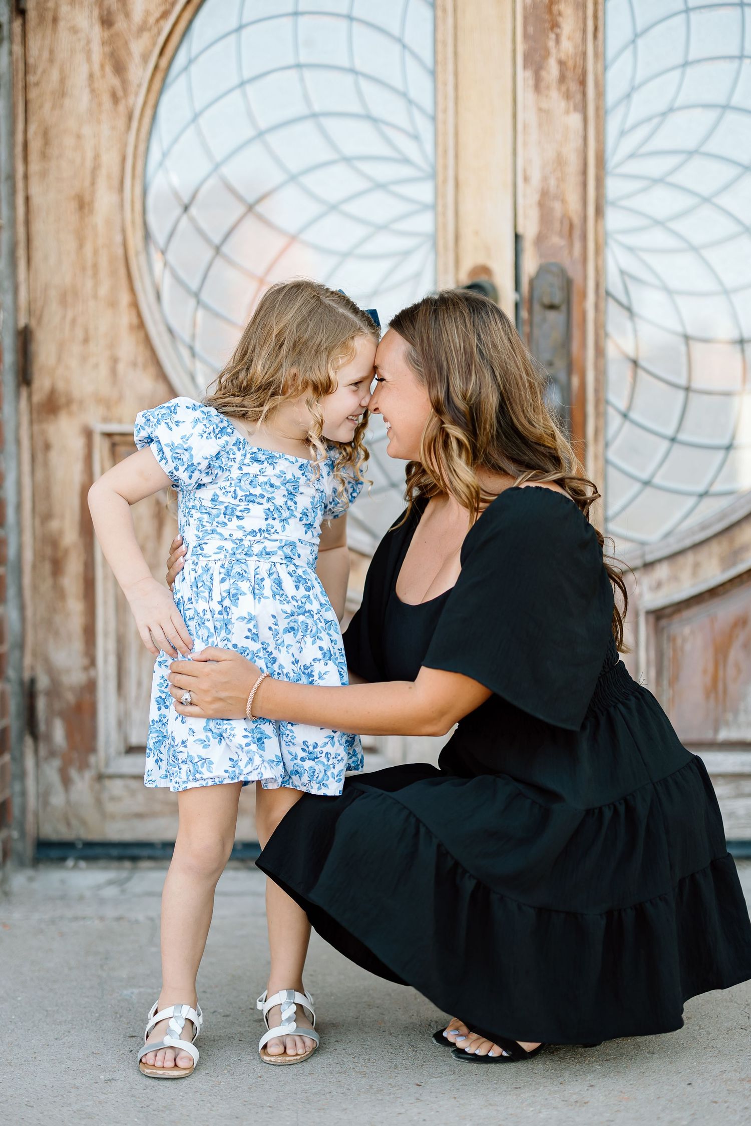 A series of four candid photos showing a tender moment between a woman in black and a child in blue floral print.