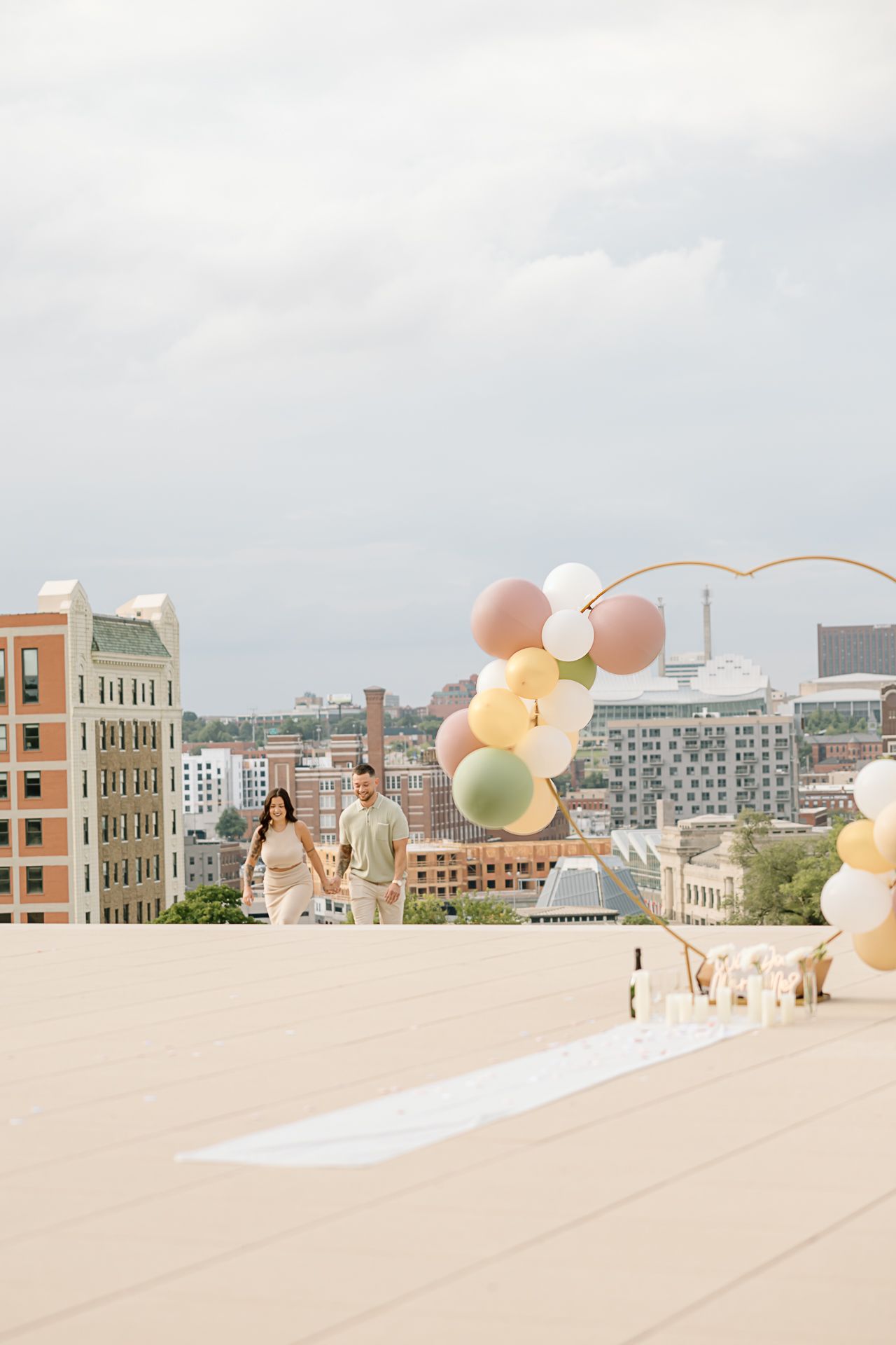 Rooftop event setup with pastel balloon arch and city skyline view.
