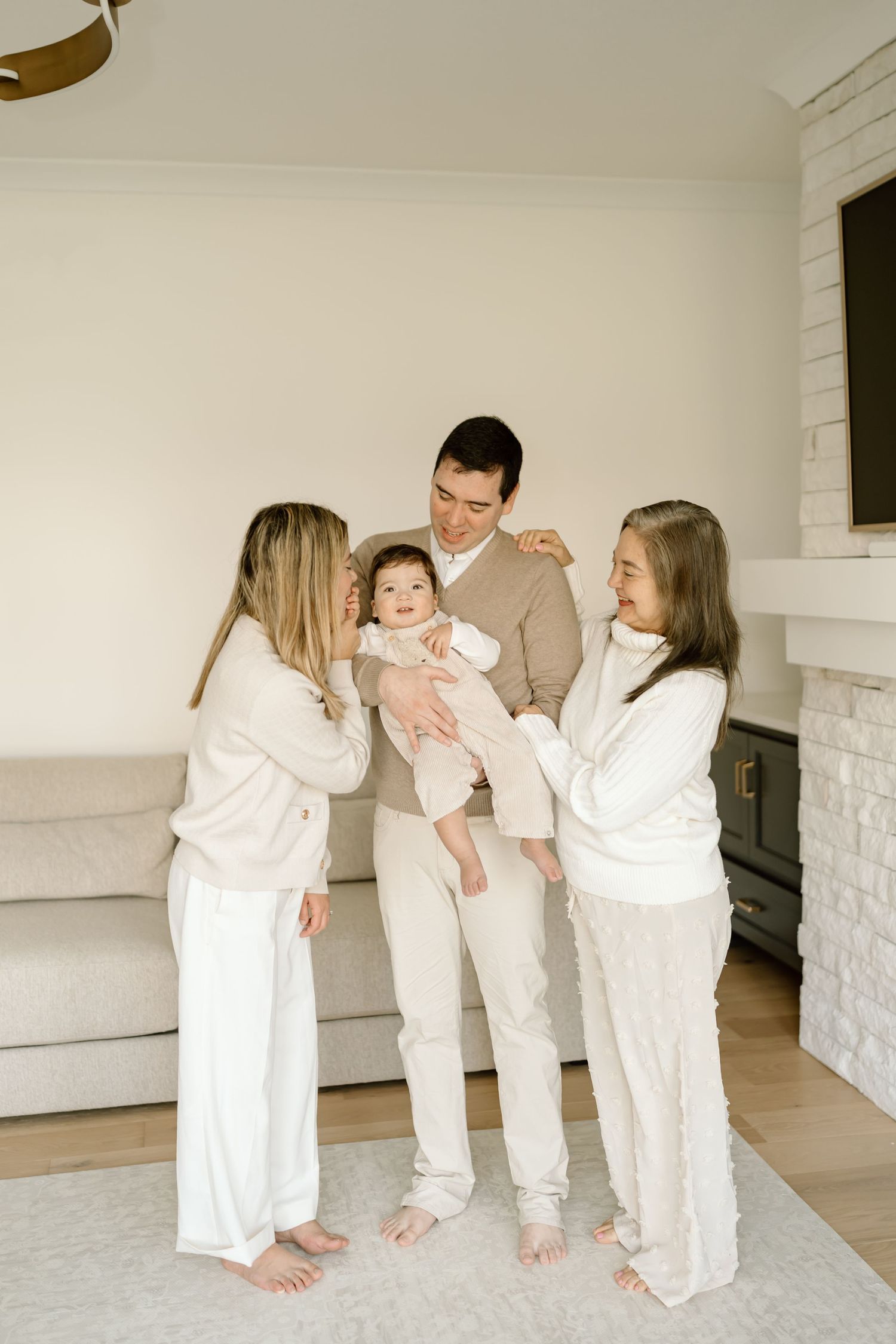 A family wearing matching white outfits plays together in a bright modern living room setting.