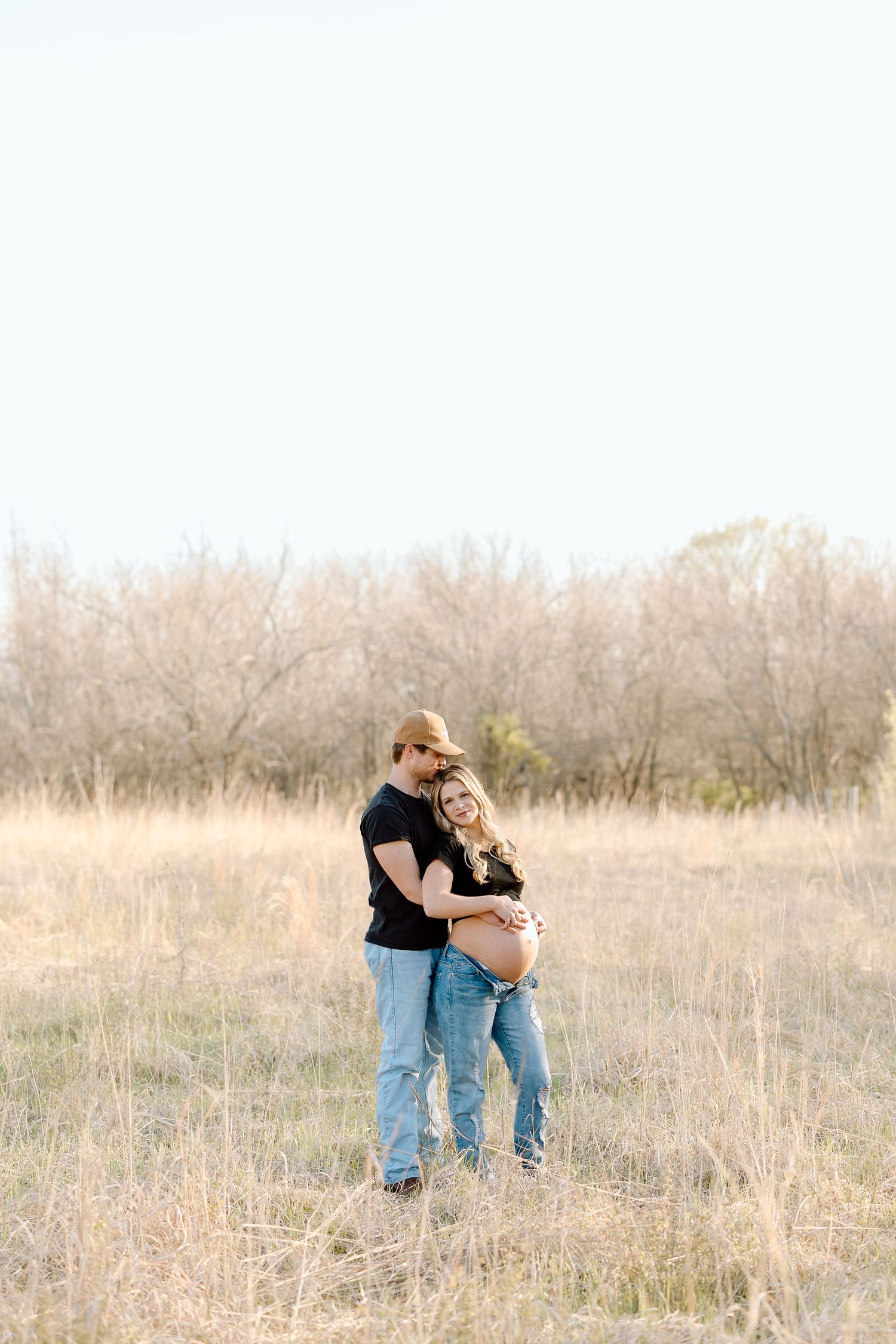 A couple shares an intimate moment together in a golden sunlit field during a romantic outdoor photoshoot.