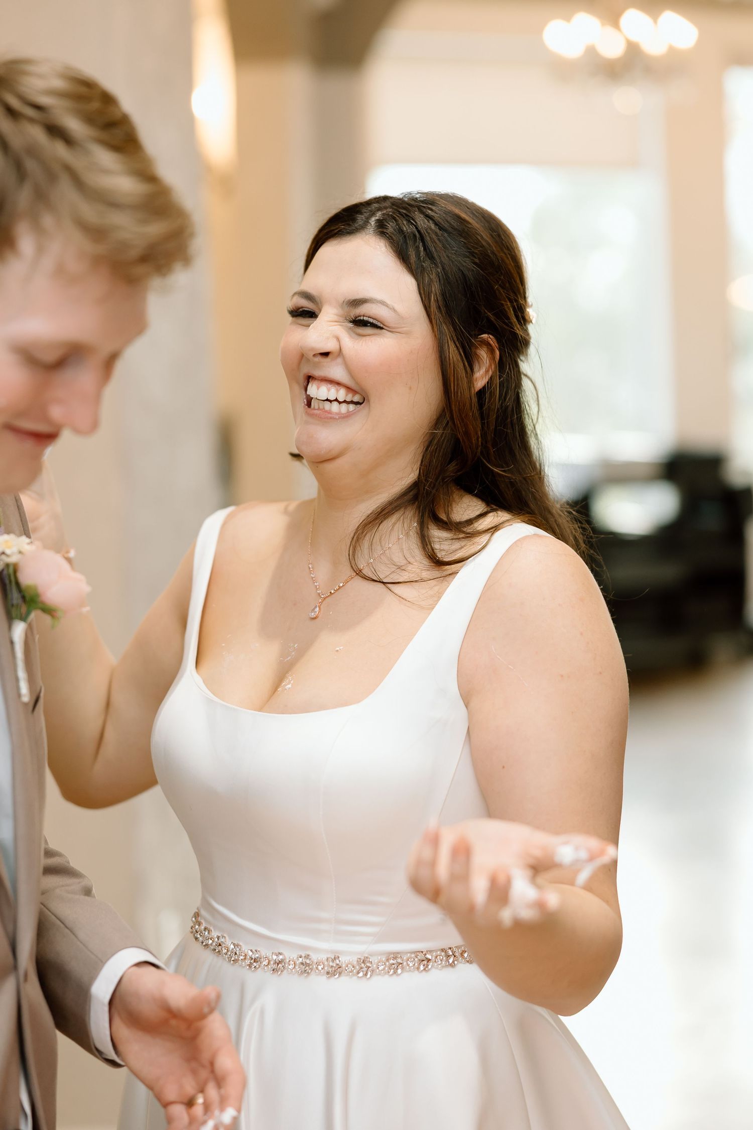 A joyful moment captured during a wedding reception as people laugh and dance together in an elegant venue.
