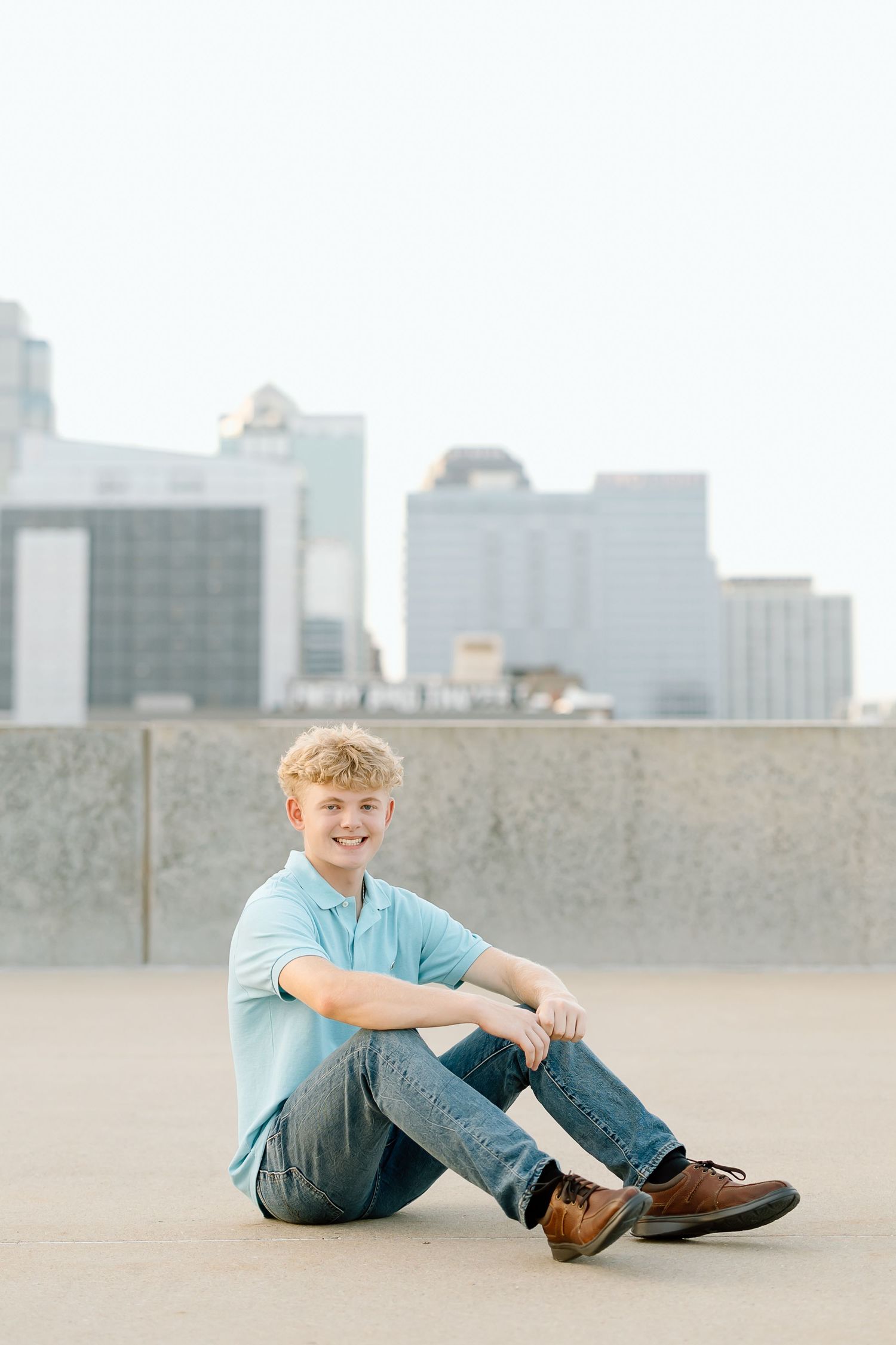 A series of four connected photos showing someone in a light blue shirt and jeans sitting on a concrete surface with a city skyline.
