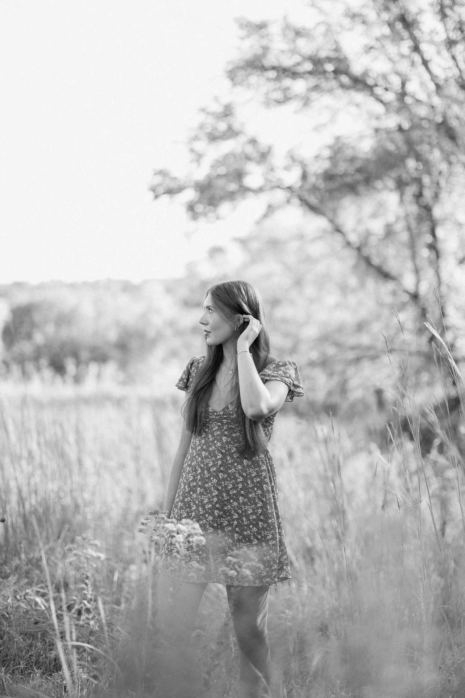 A child in a floral dress plays in a dreamy field of tall grass and wildflowers on a summer afternoon.