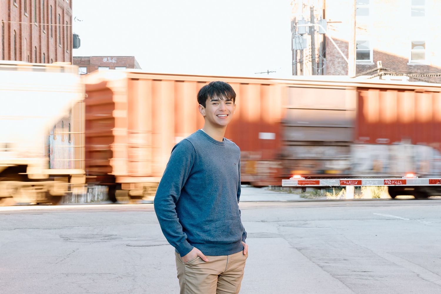Urban portrait with person in blue sweater standing near industrial shipping containers.