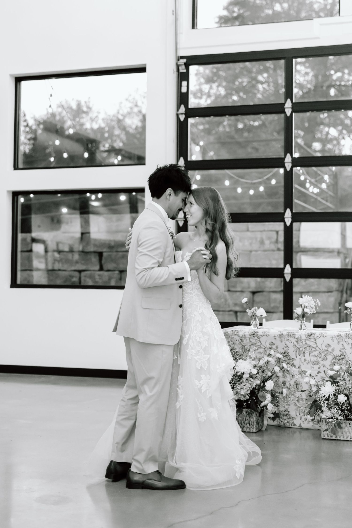 Bride and groom sharing their first dance in black and white photo at elegant wedding reception venue.