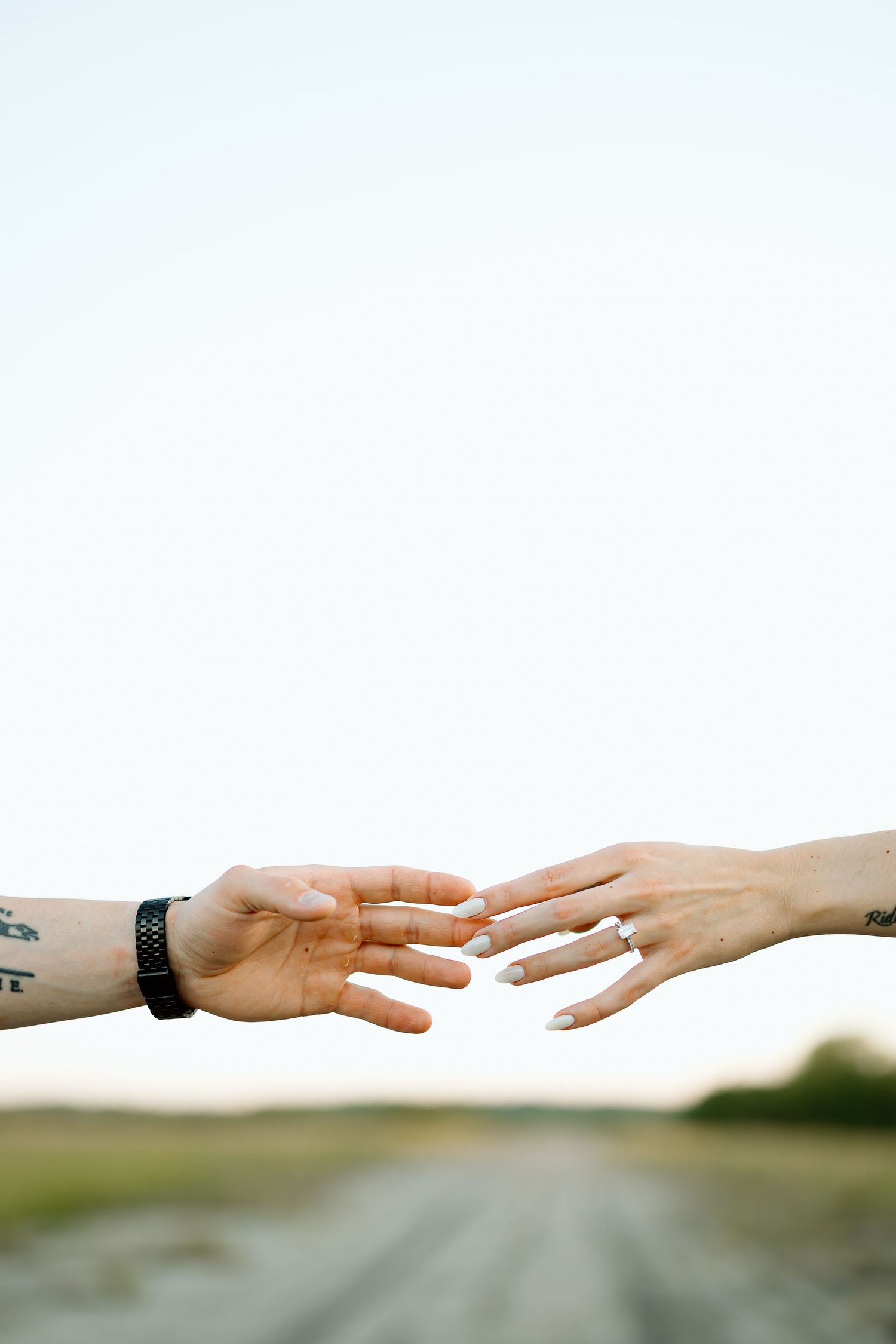 Two hands reaching out to touch each other against a blurred outdoor background, reminiscent of connection and support.
