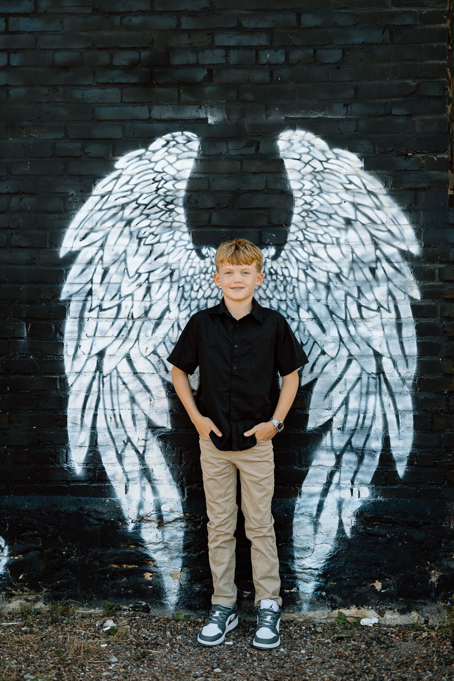 A sequence of photos showing someone posing against a black brick wall with white painted angel wings graffiti art.