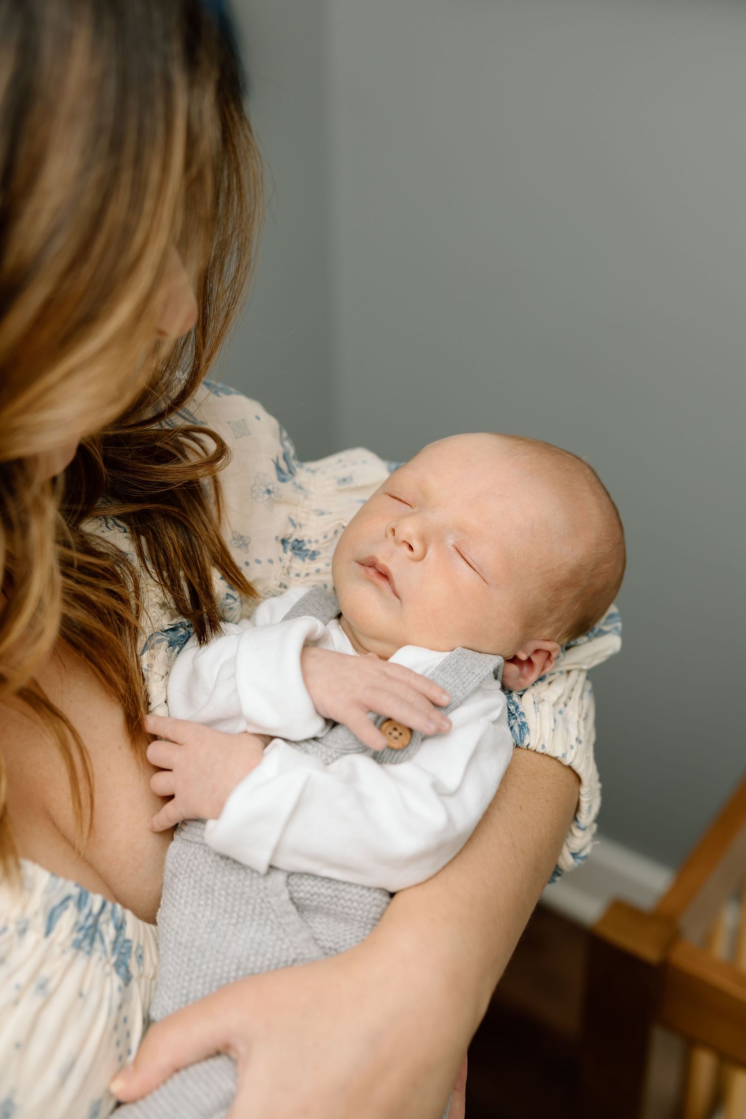 A sleeping newborn baby wearing white clothing is cradled in someone's arms in a series of tender moments.
