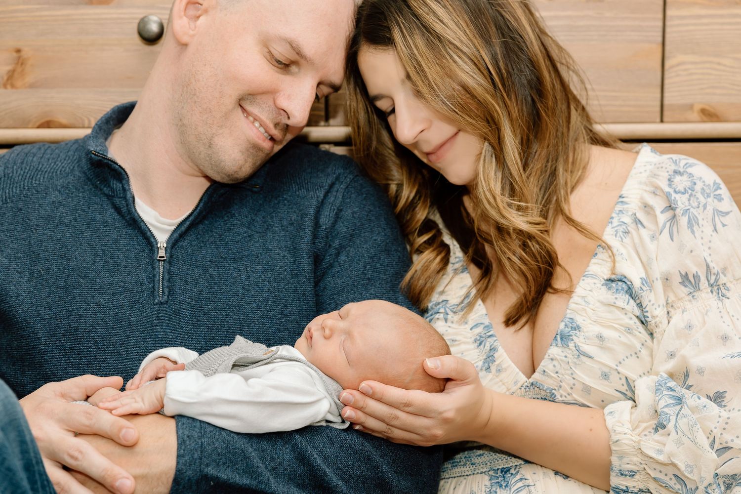 A series of intimate photos showing a couple lovingly gazing at their newborn baby in a cozy home setting.