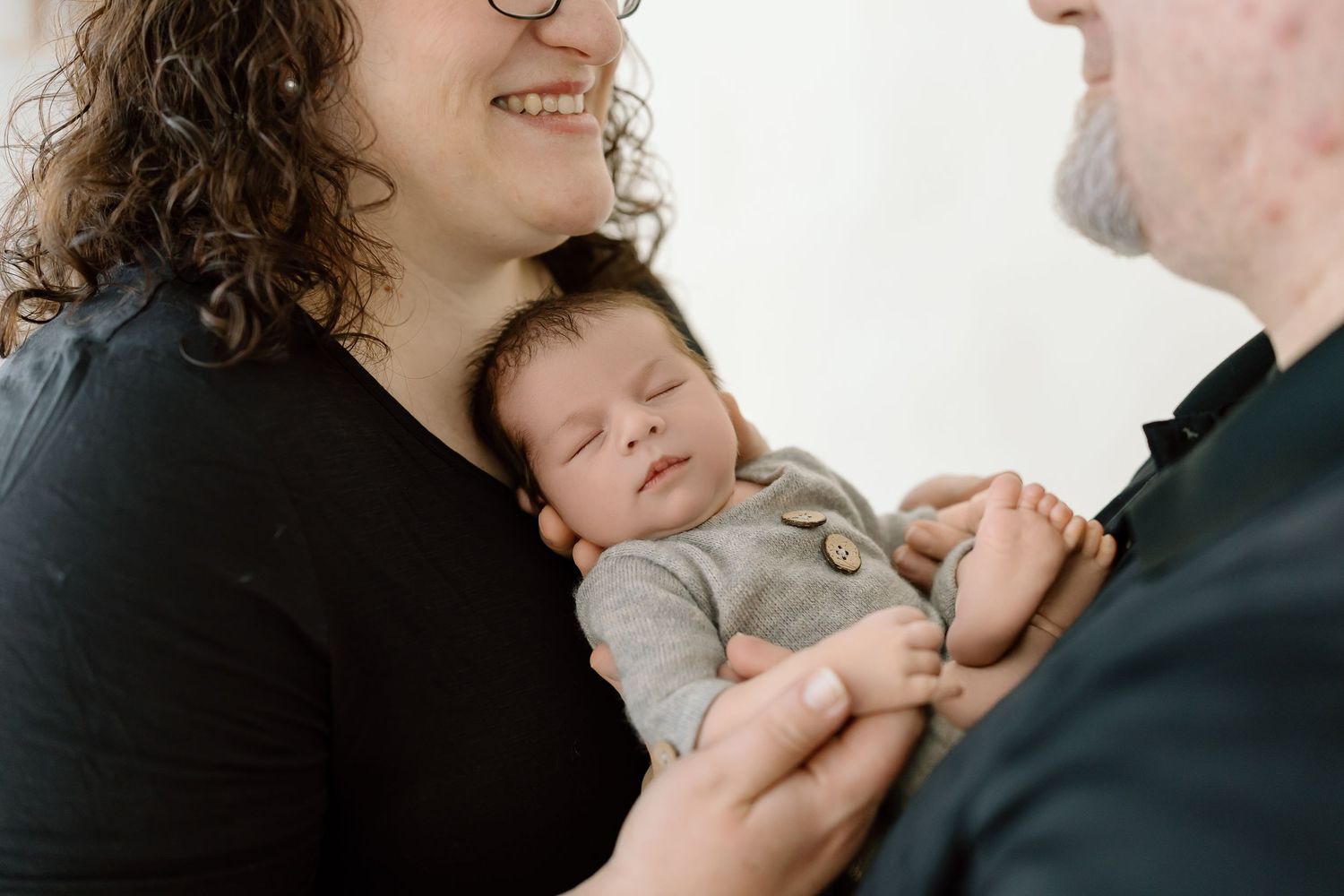 A series of intimate black and white photographs showing tender moments between parent and baby.