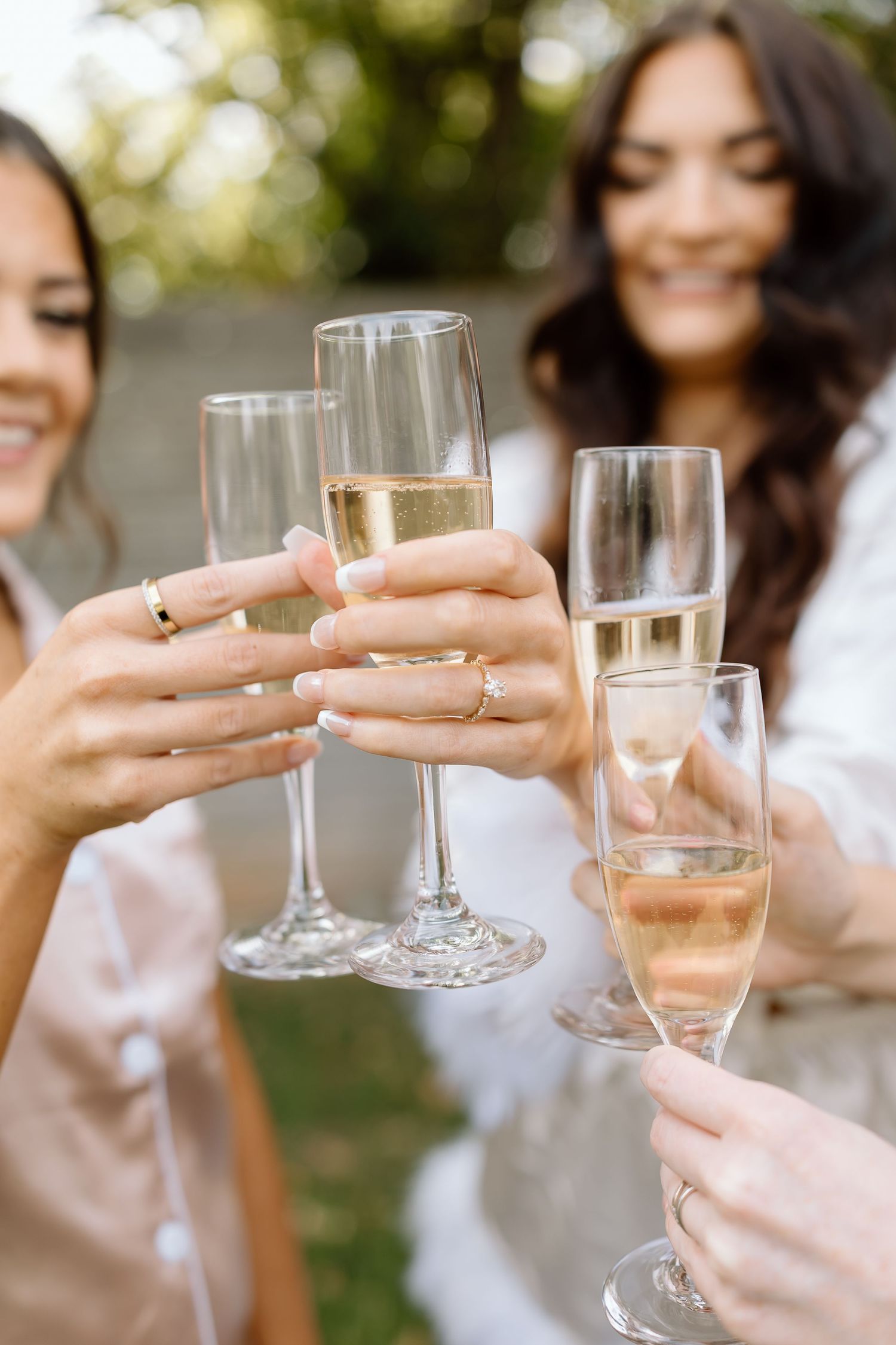 A group of people in white clothing toasting with champagne glasses outdoors during a celebration.