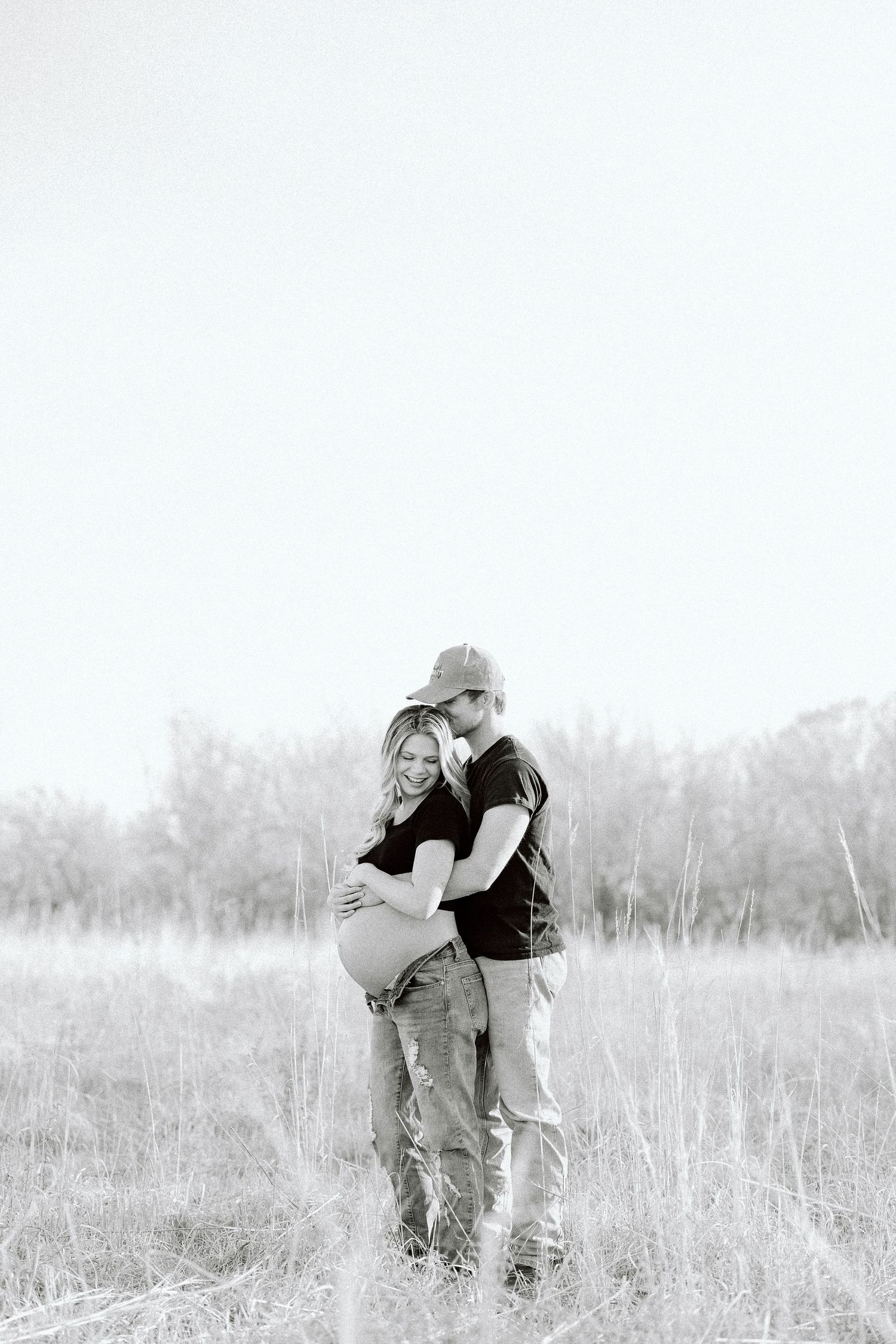 A romantic black and white photo series shows a couple embracing in a serene meadow setting.