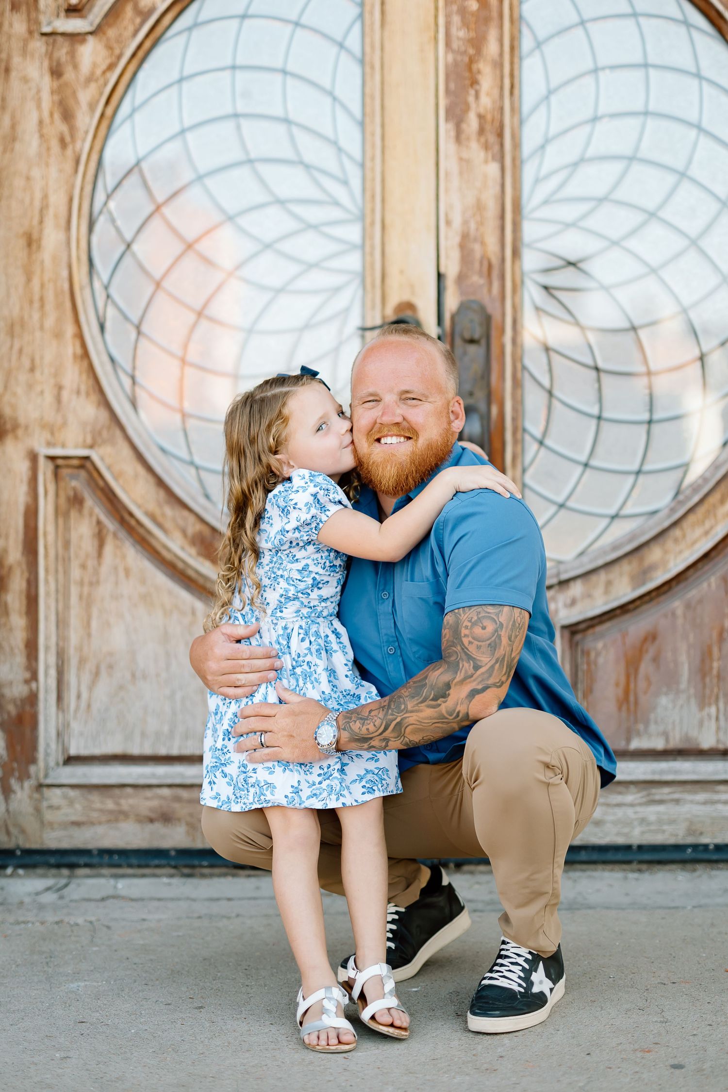 Sweet moment captured against rustic wooden door background with circular window designs.