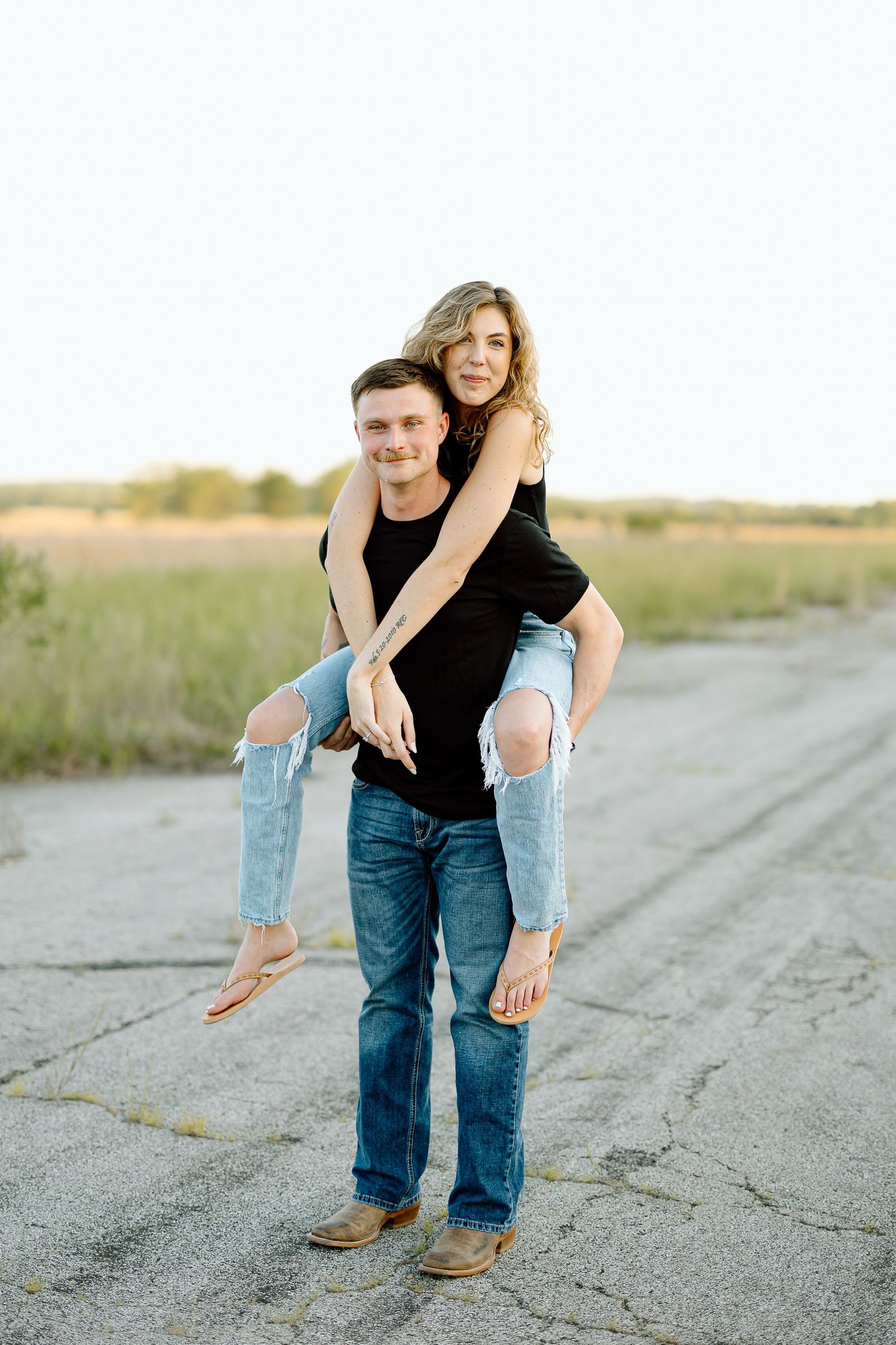 Three photos of a couple in casual attire posing playfully on a rural road at sunset.