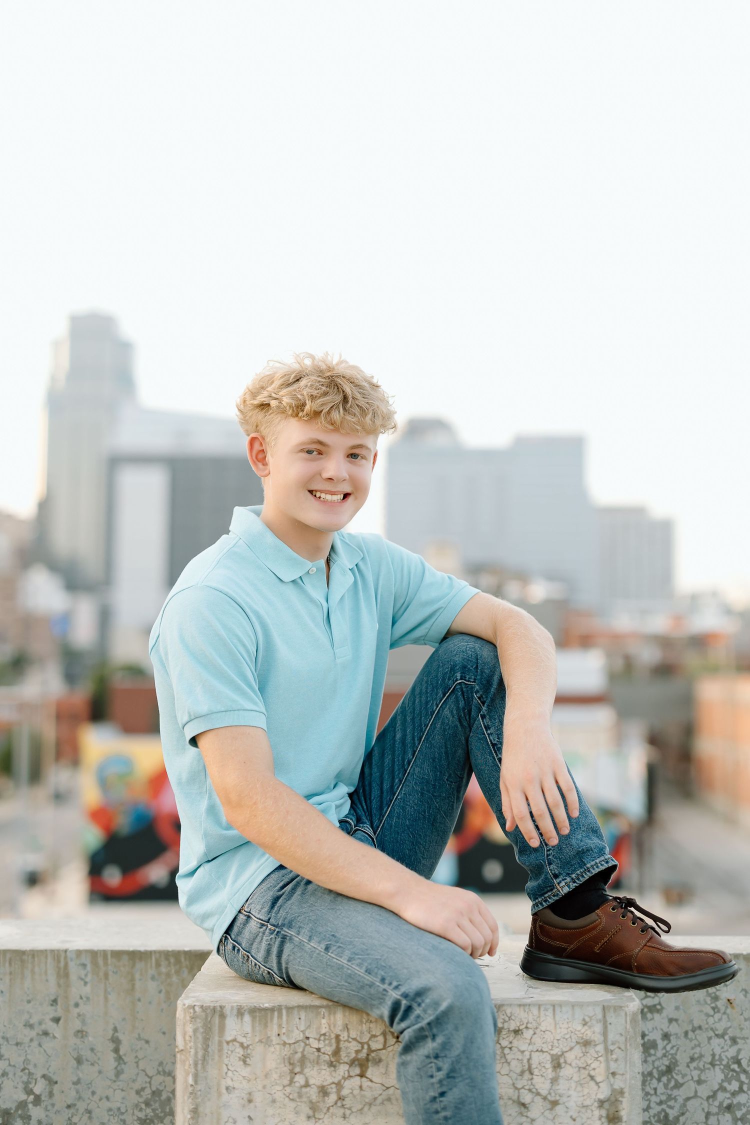 Three similar photos of someone in a light blue shirt sitting on a concrete wall with a city skyline in the background.