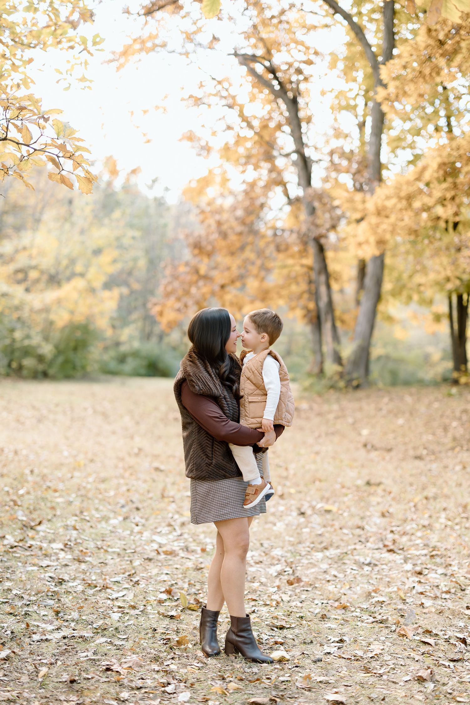 A tender autumn moment captured in a park with golden leaves falling from trees in the background.