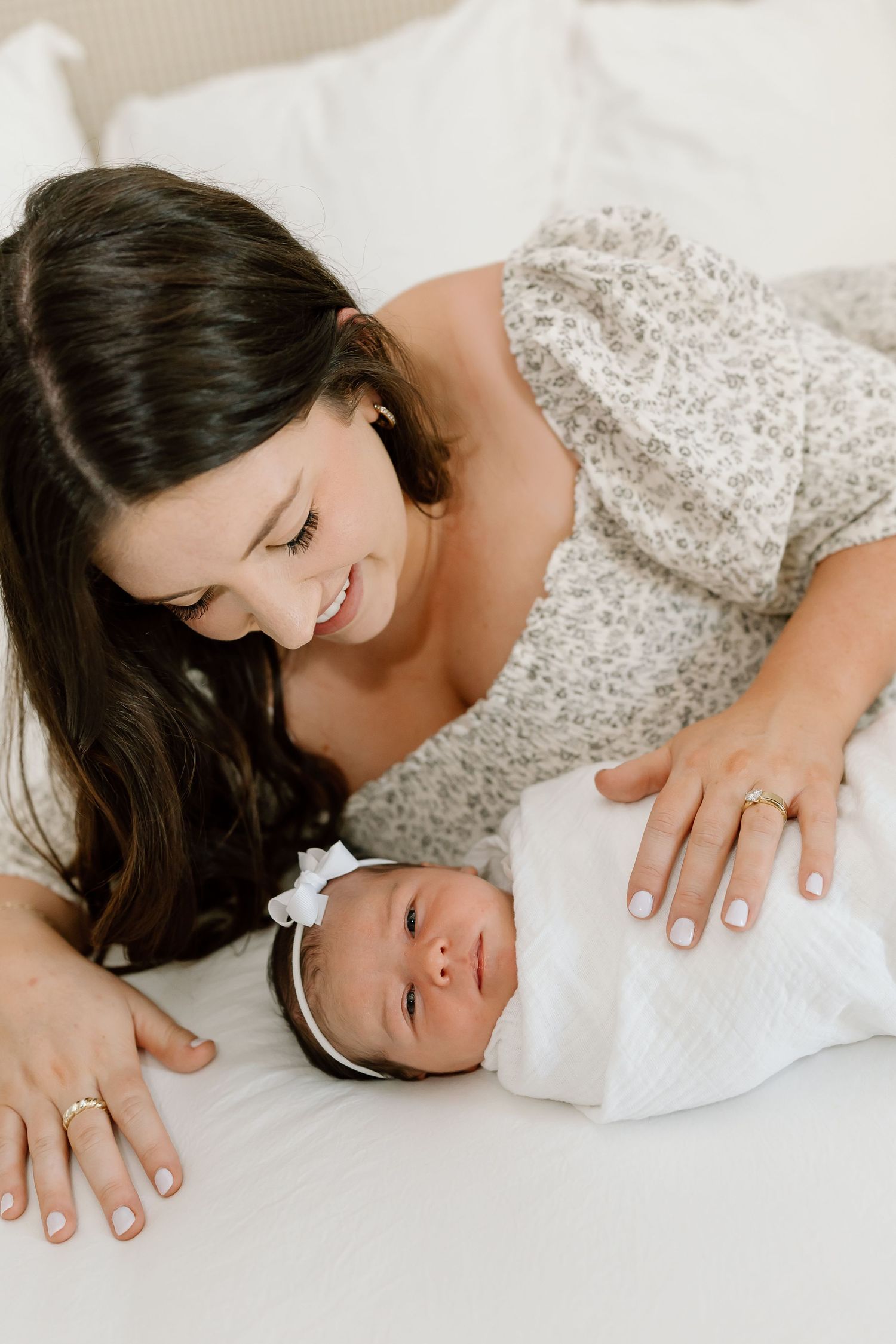 A tender moment between parent and newborn baby captured in soft white tones during an intimate photography session.