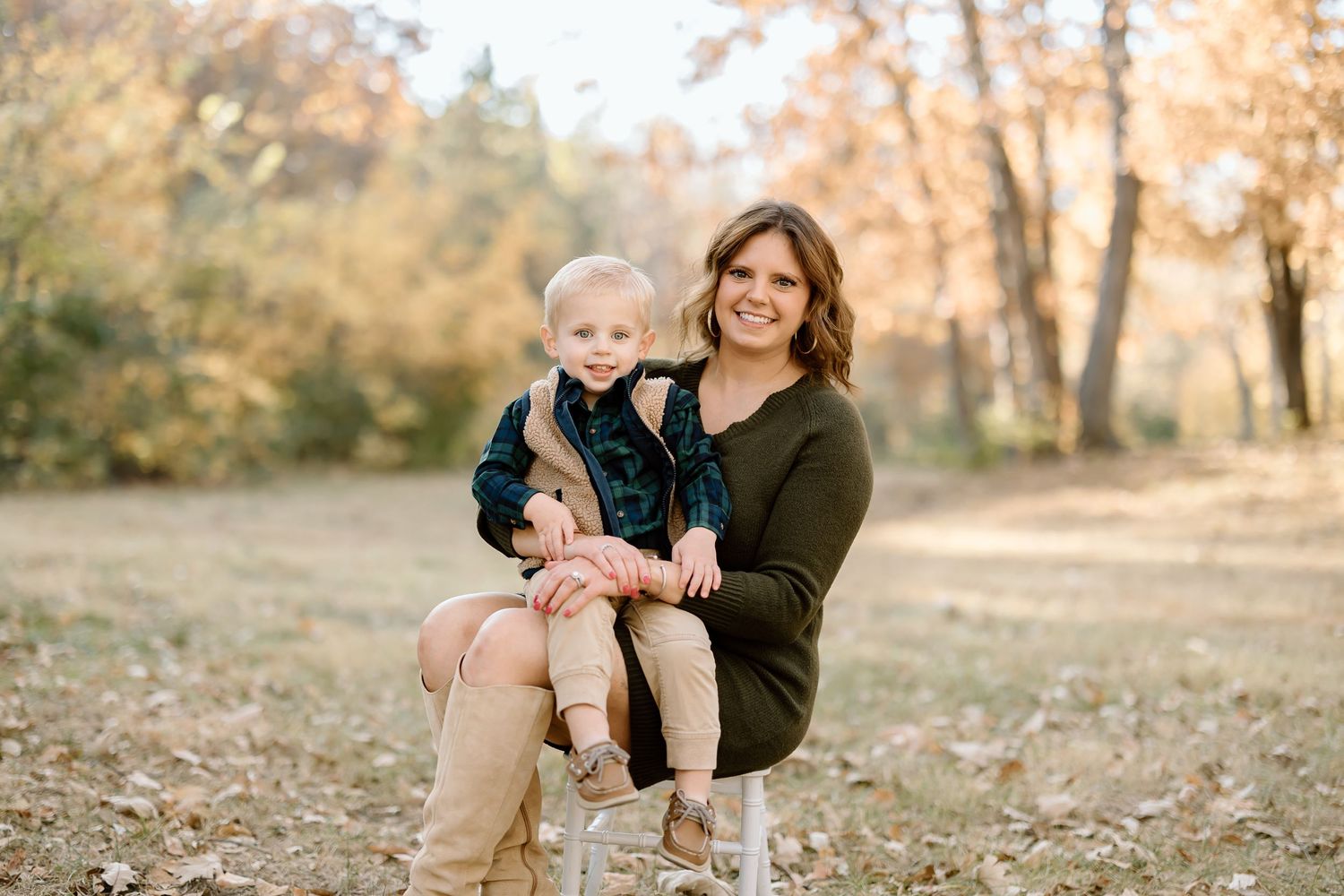 Outdoor family portrait on white chair with fall foliage in background.