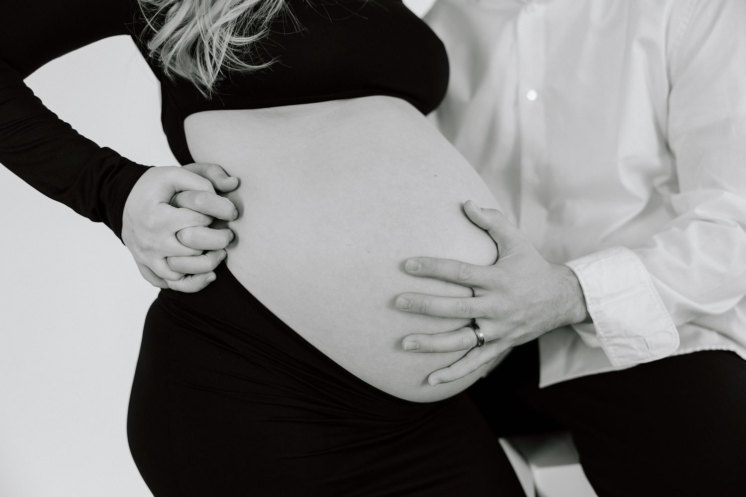 Black and white close-up of hands cradling pregnant belly.