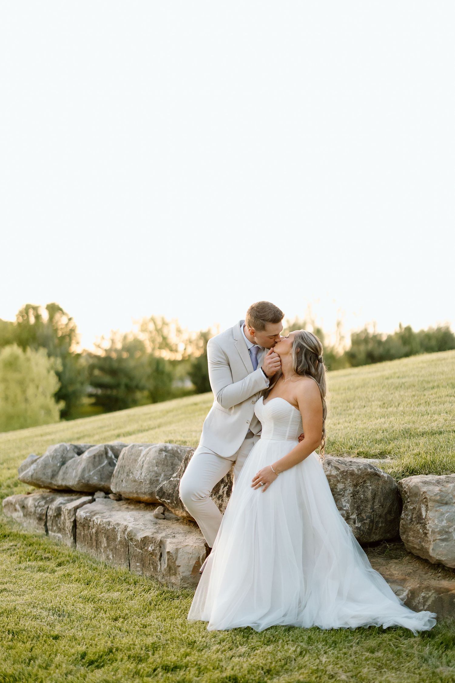 Wedding couple embraces on stone steps during golden hour photography.