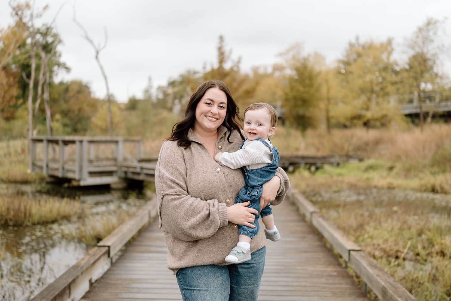 A series of outdoor family portraits on a rustic wooden bridge surrounded by autumn foliage and natural scenery.