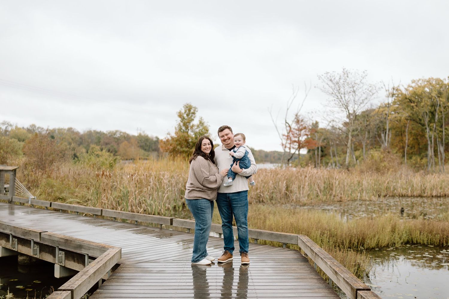 Couple walking together on a wooden boardwalk through autumn wetlands on an overcast day.