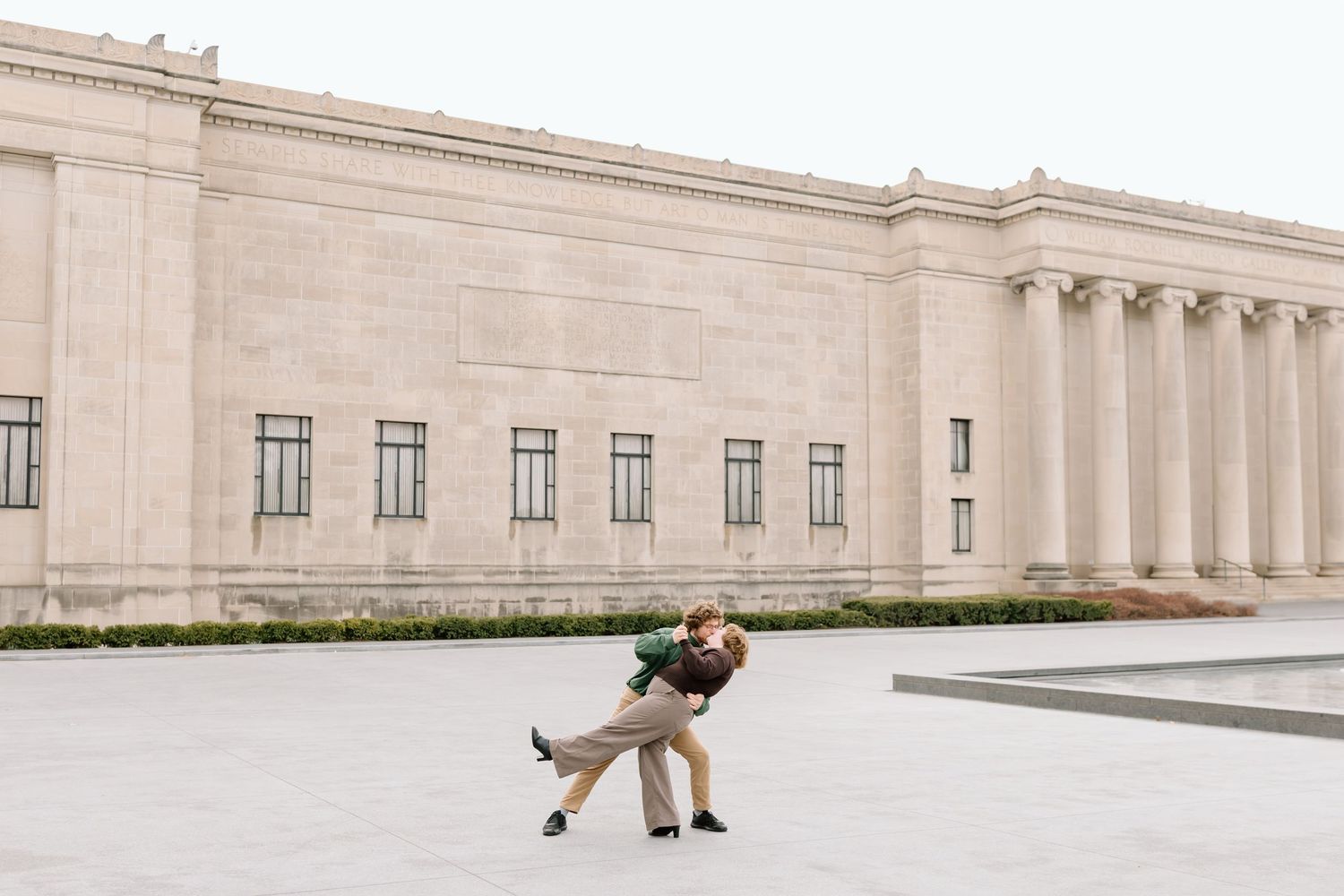 Person walking across the expansive plaza in front of a grand neoclassical building with columns.