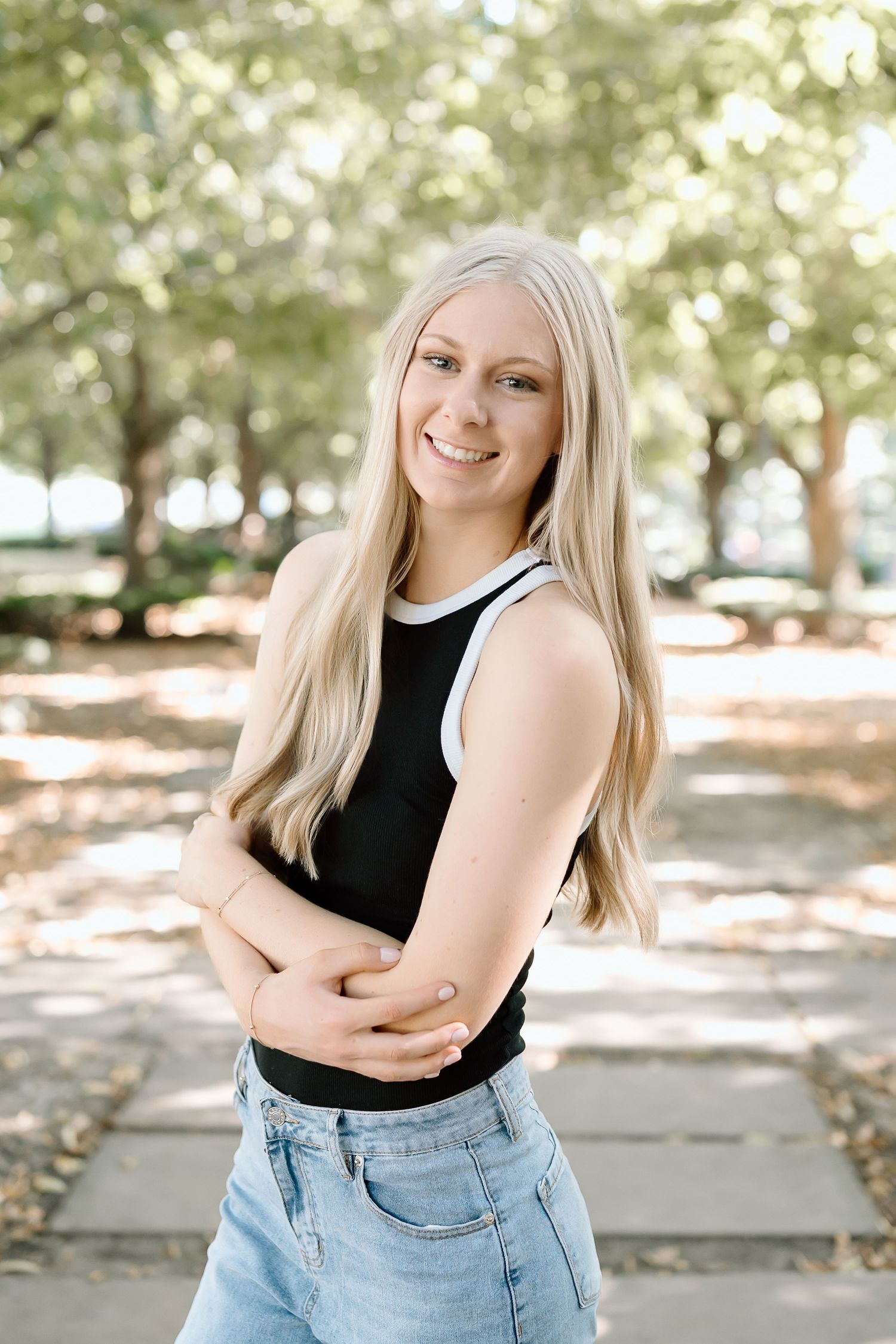 A series of casual outdoor portraits showing a person in a black sleeveless top and light denim against a natural background.