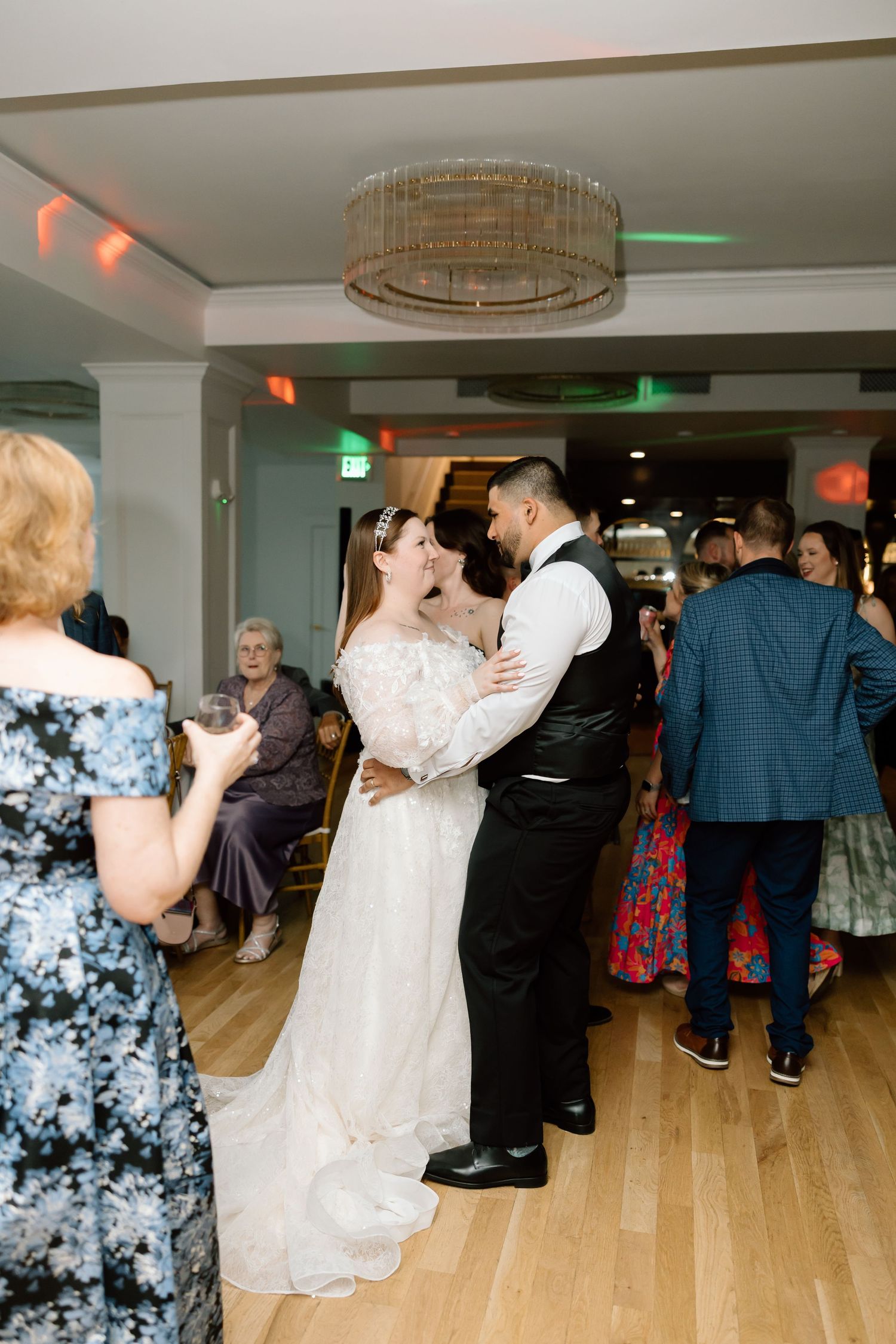 Bride and groom share their first dance at wedding reception with guests watching in elegant venue.