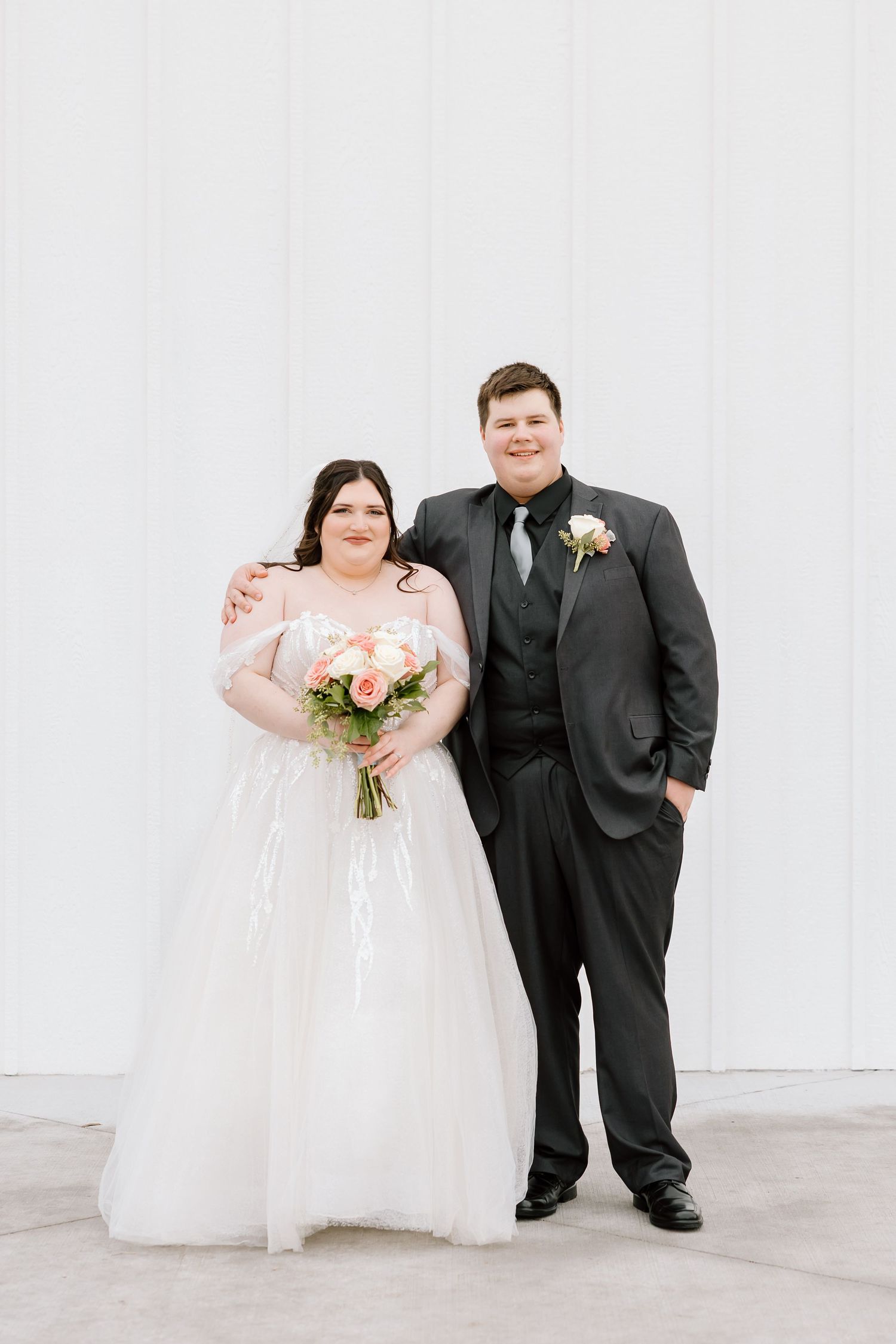 A bride and groom in formal wedding attire pose together against a white wall in a series of candid shots.