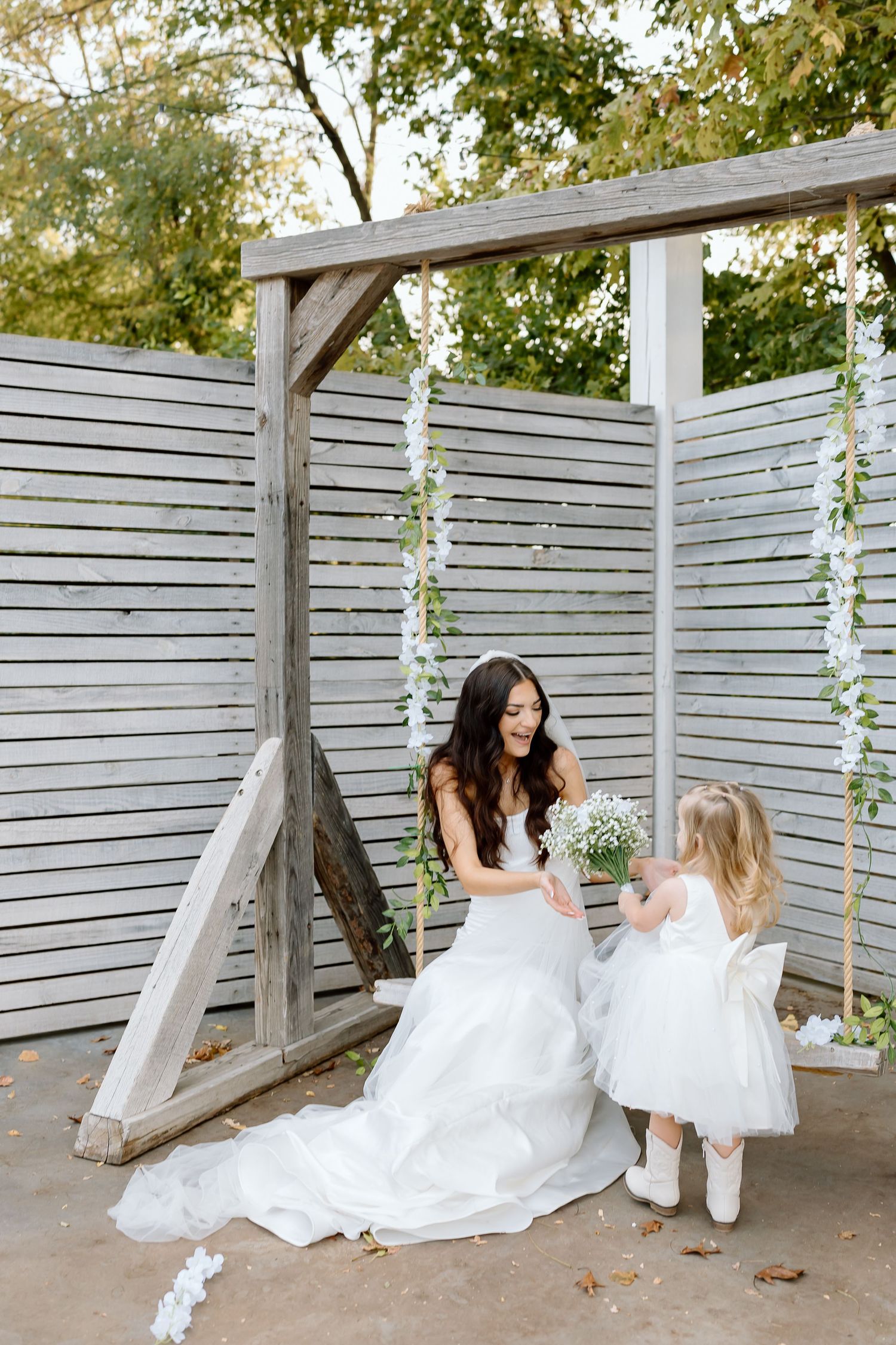 A romantic wedding photo sequence showing a couple in white attire sitting together on a wooden bench against a slatted wall.