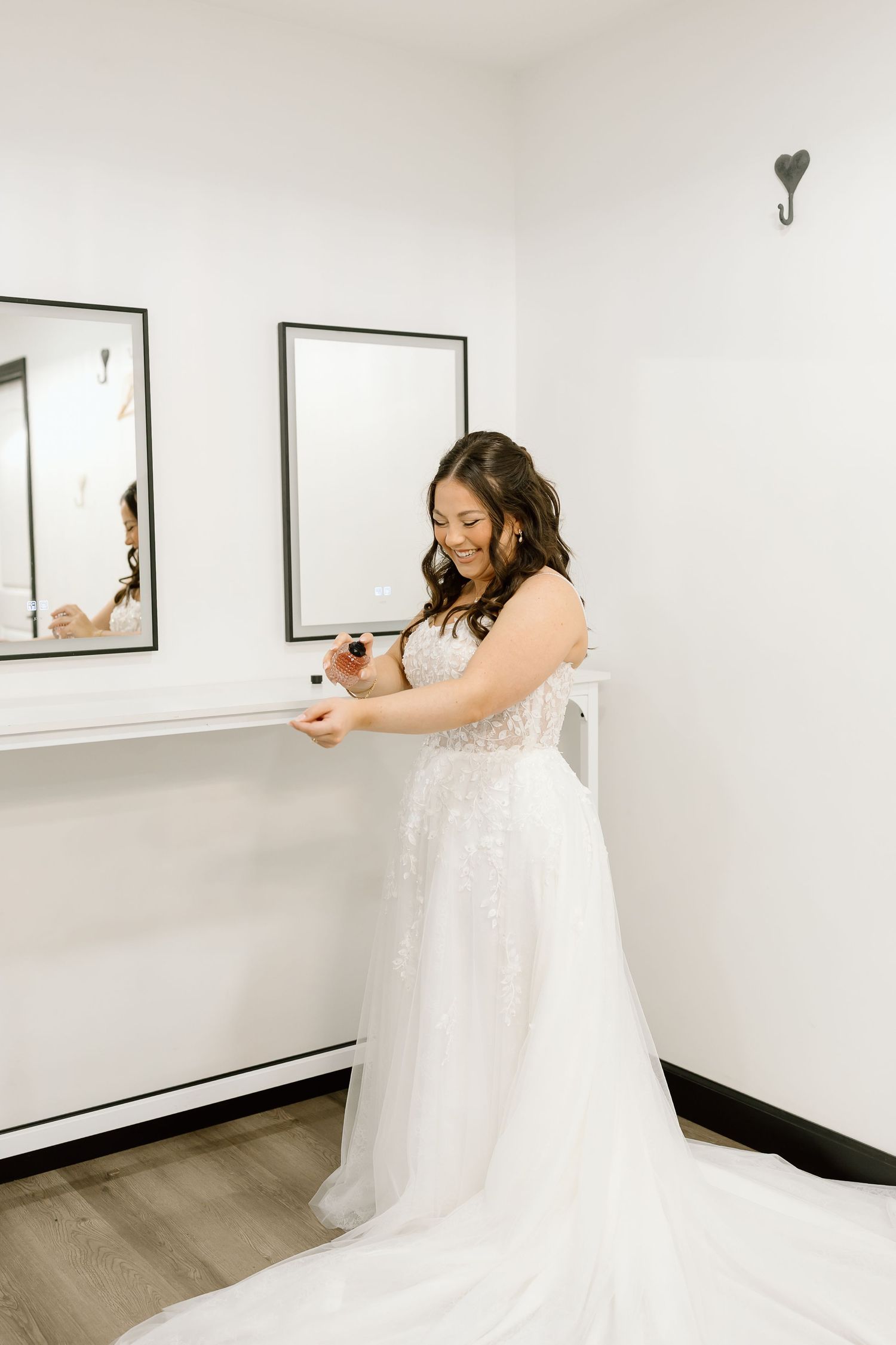 A bride in a flowing white dress spins and twirls gracefully in a bright minimalist room with framed artwork on the walls.