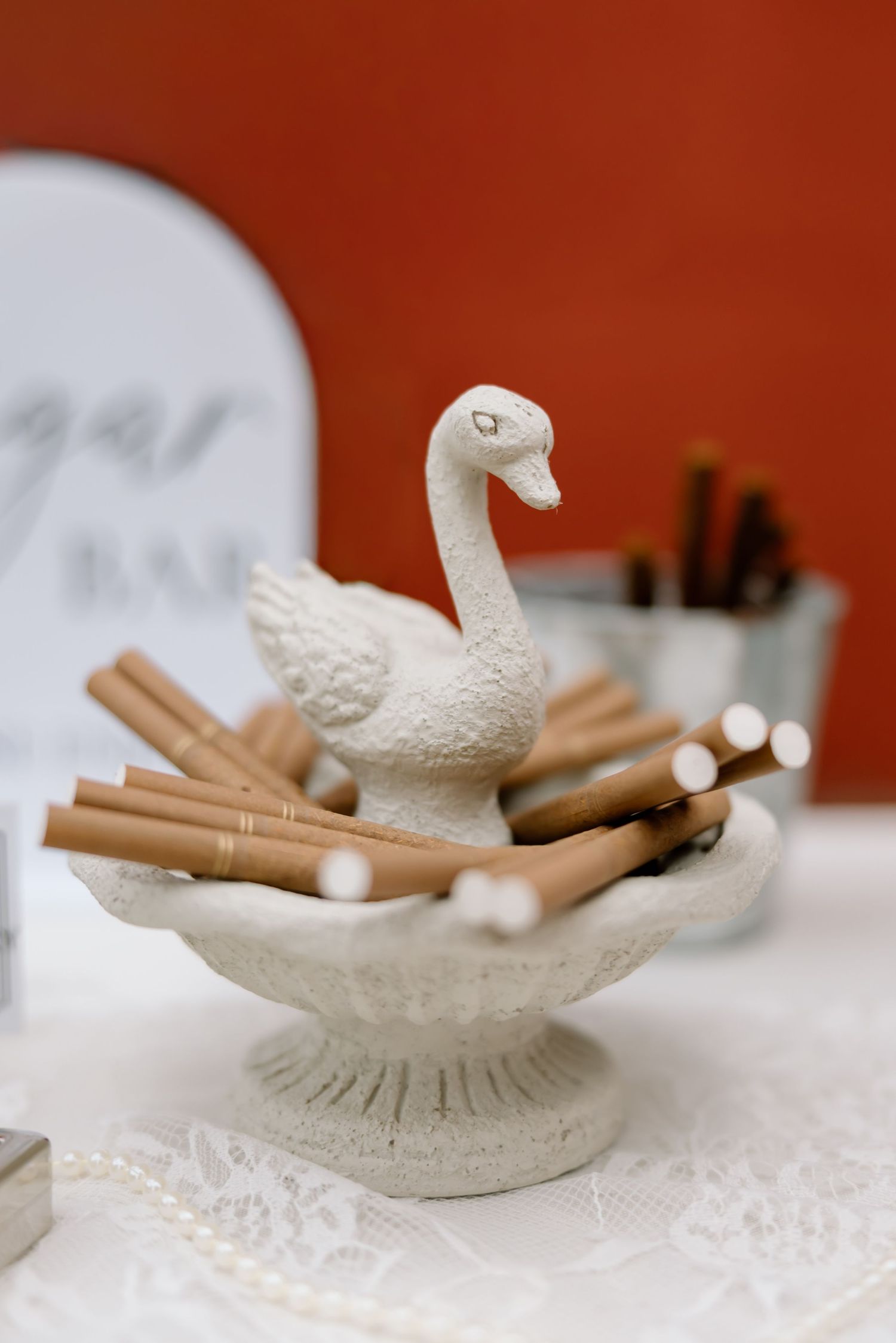 White swan figurine bowl filled with cinnamon sticks displayed on a lace tablecloth at a sugar bar.