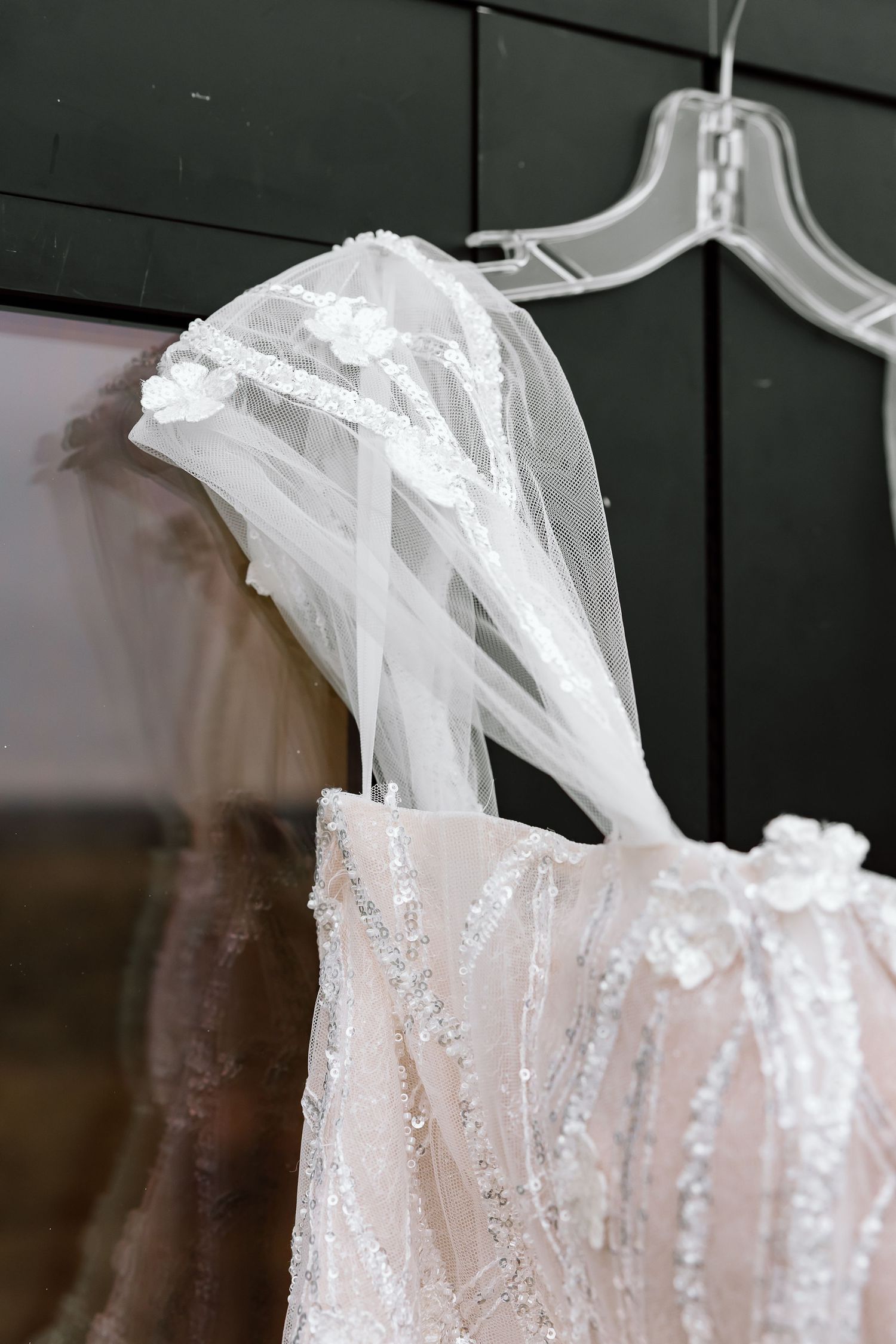 A row of white wedding dresses with sequins and sparkles hanging on garment racks in a bridal shop.