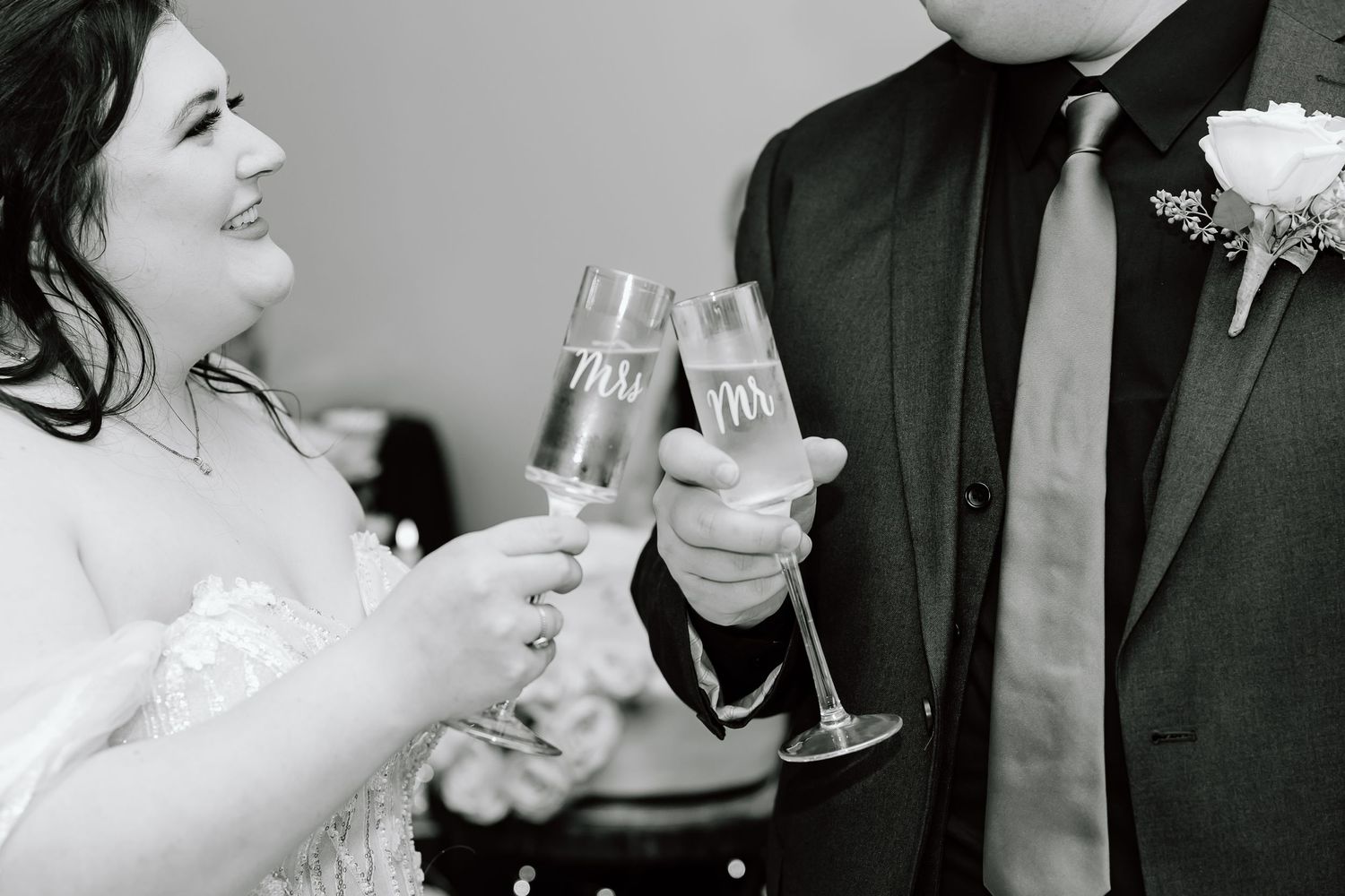 Black and white photo of couple toasting with champagne glasses at wedding reception.