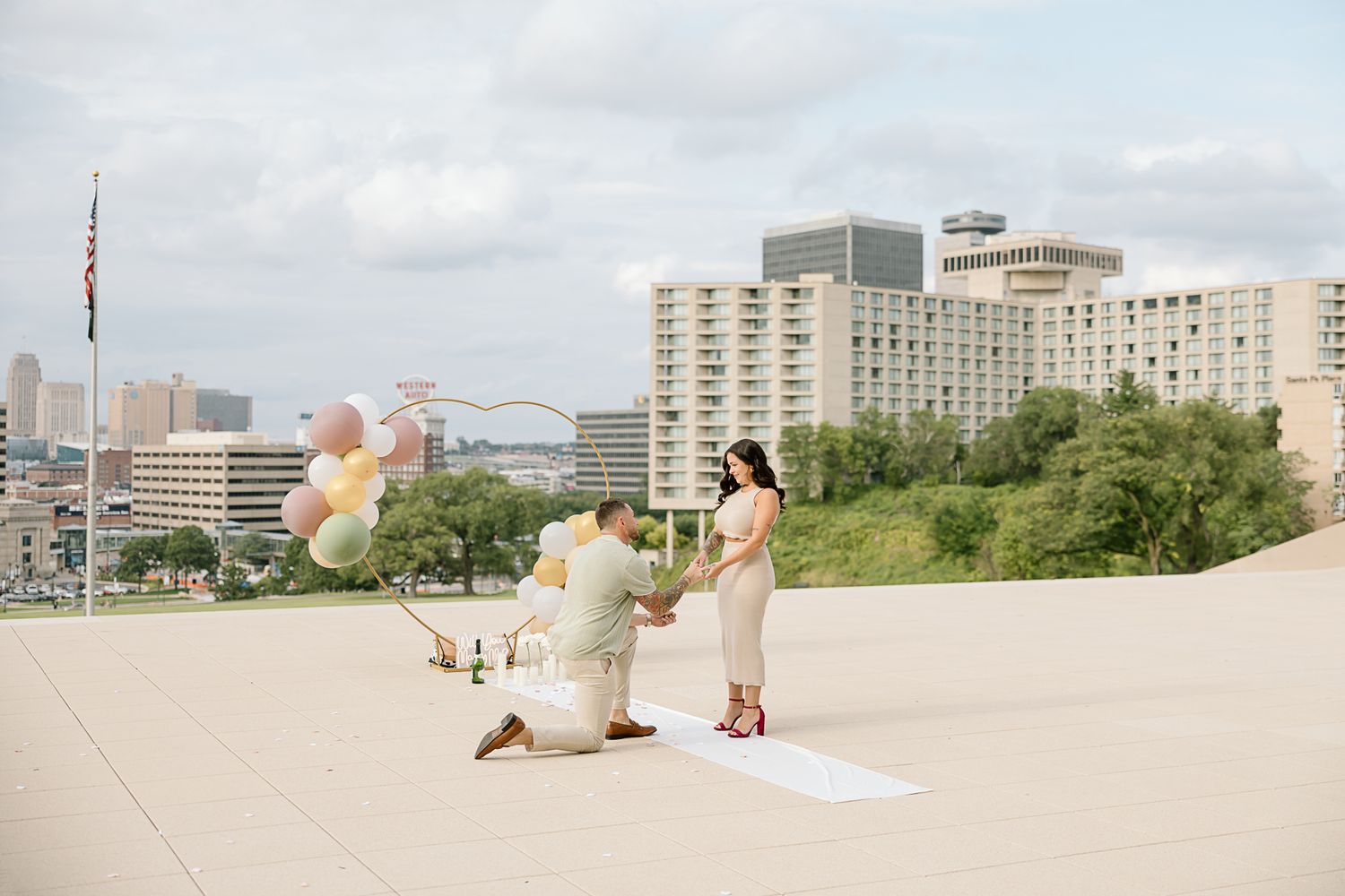A proposal scene with balloons on a city rooftop overlooking urban buildings.